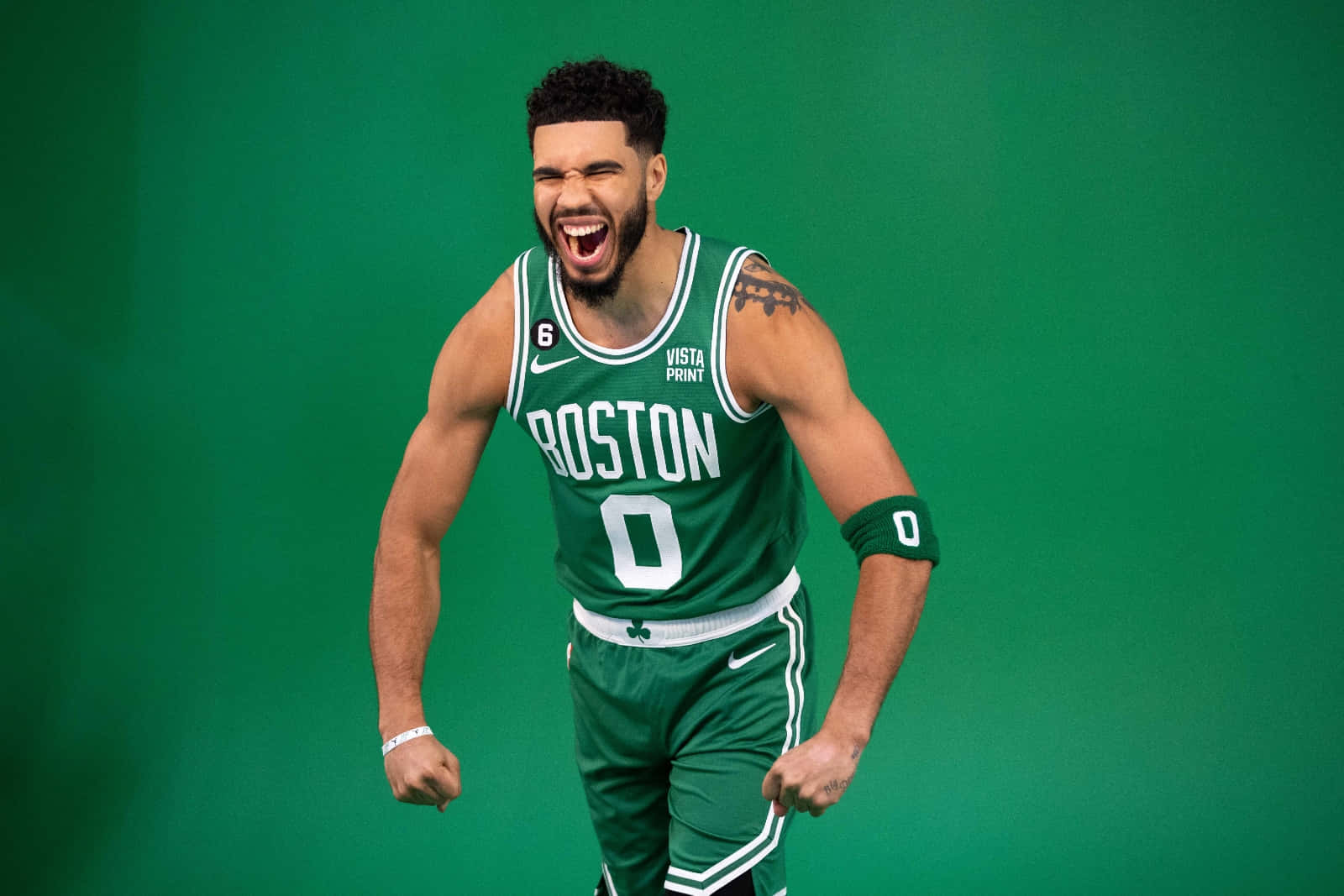 Celtics 桌布 壁紙 — 一名身穿綠色波士頓塞爾提克球衣的籃球運動員在純綠色背景下勝利咆哮。