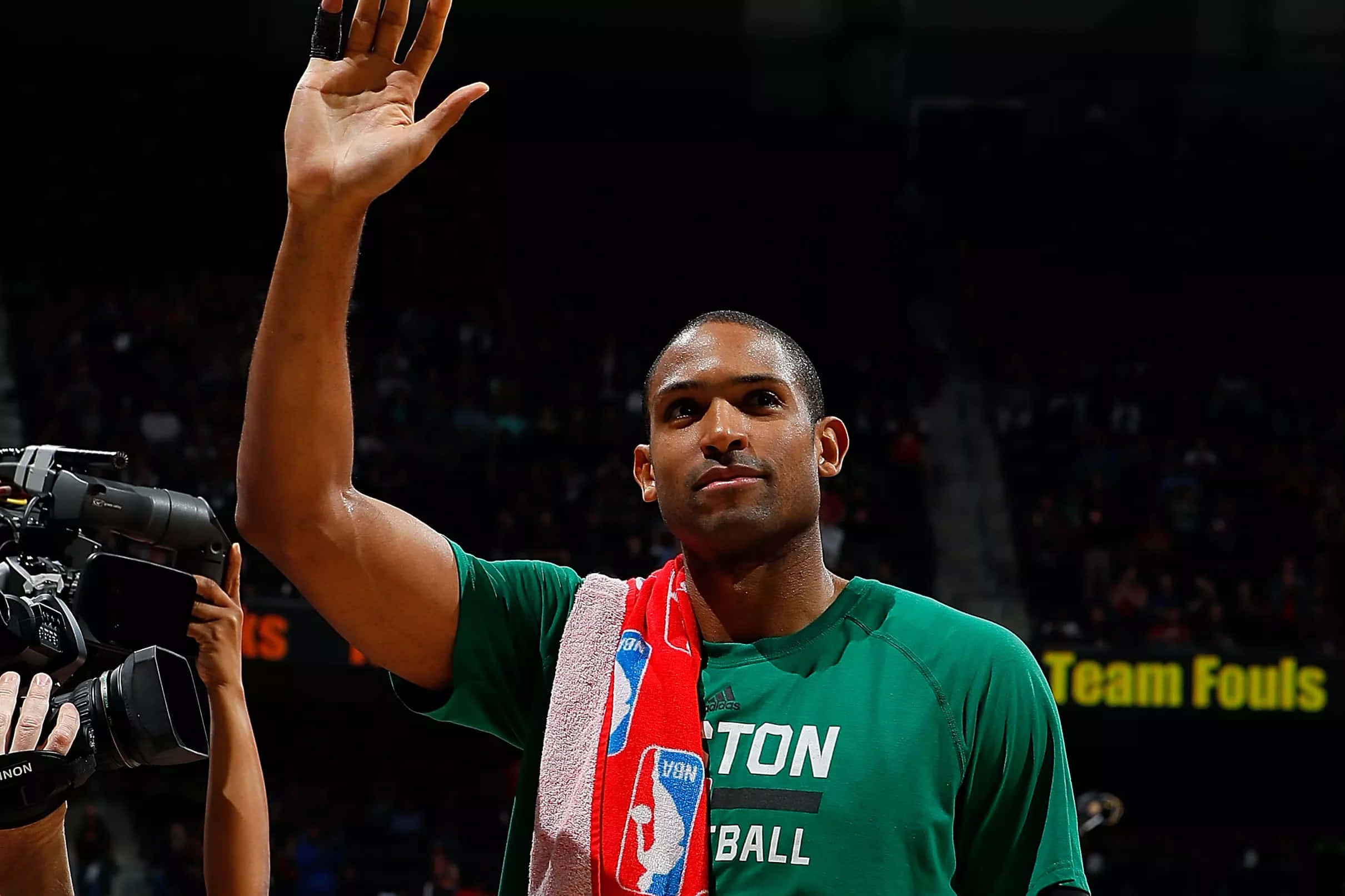 Al Horford 桌布 壁紙 — 一名身穿綠色波士頓塞爾提克球衣的籃球運動員，在比賽中將紅色毛巾搭在肩上，向球迷揮手。