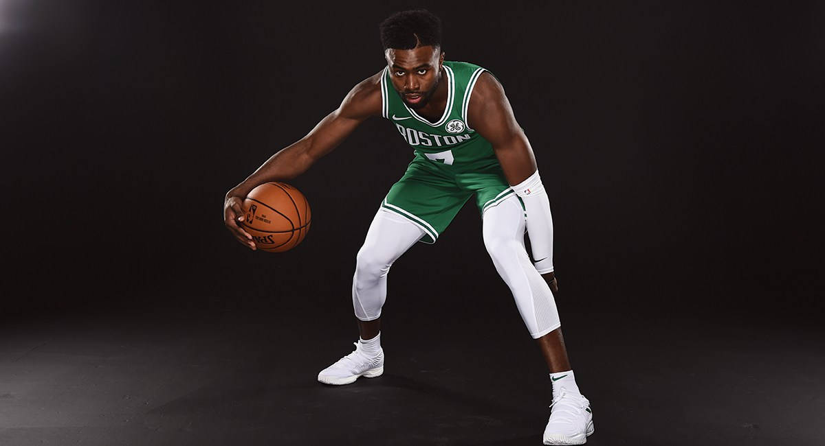 Jaylen Brown 桌布 壁紙 — 一名身穿綠色波士頓球衣的籃球運動員在黑色攝影棚背景下以低姿勢運球。
