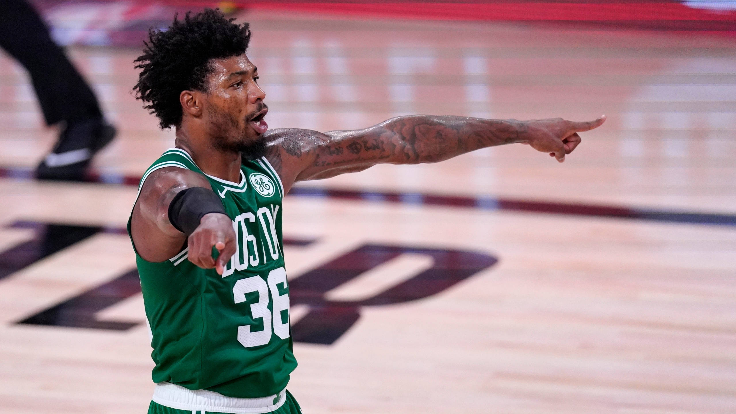 Marcus 桌布 壁紙 — 一名身穿綠色球衣、背號36的籃球運動員在拋光木地板上比賽時強調性地指著。