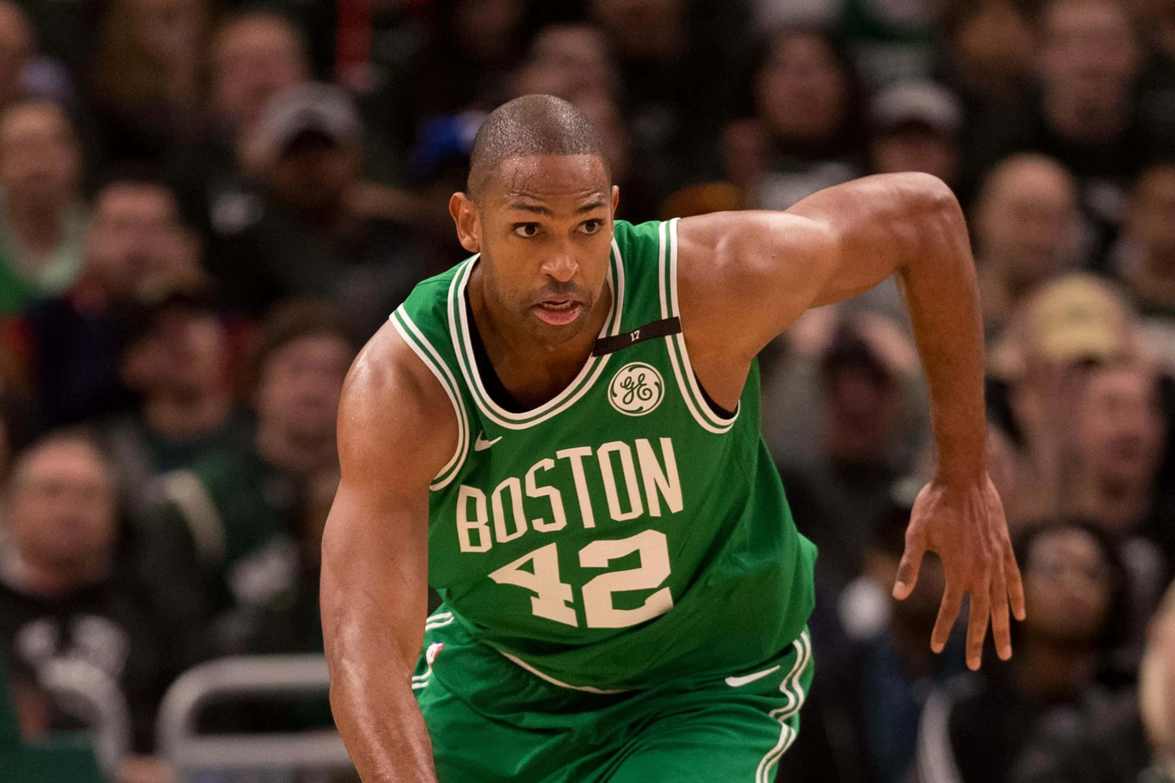 Al Horford 桌布 壁紙 — 一名身穿綠色球衣、號碼42的波士頓塞爾提克籃球運動員在比賽中激烈運球，背景是模糊的人群。