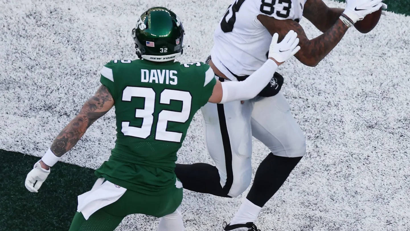 Ny Jets 桌布 壁紙 — 一名身穿綠色球衣32號的美式足球員正在擒抱一名身穿白色球衣83號、在雪地上接球的接球員。