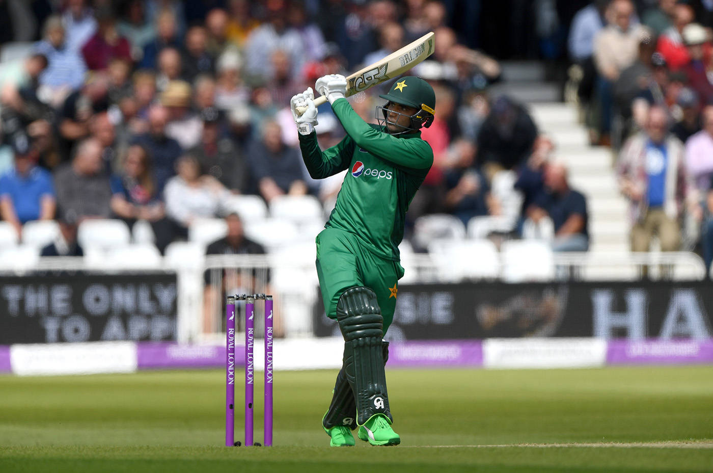 Fakhar Zaman 桌布 壁紙 — 一名身穿綠色球衣的巴基斯坦板球擊球手在日間比賽中強力揮棒，背景有觀眾。
