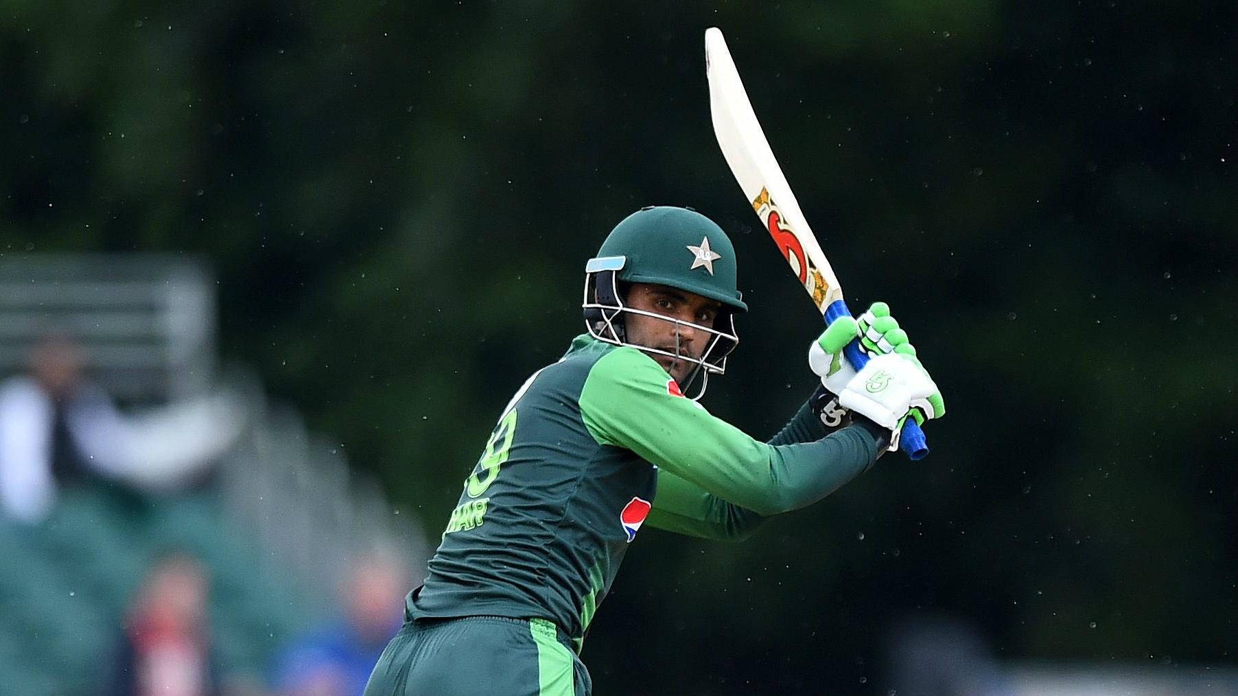 Fakhar Zaman 桌布 壁紙 — 一名身穿綠色球衣的巴基斯坦板球運動員在雨中比賽中揮動球棒，背景有模糊的觀眾。