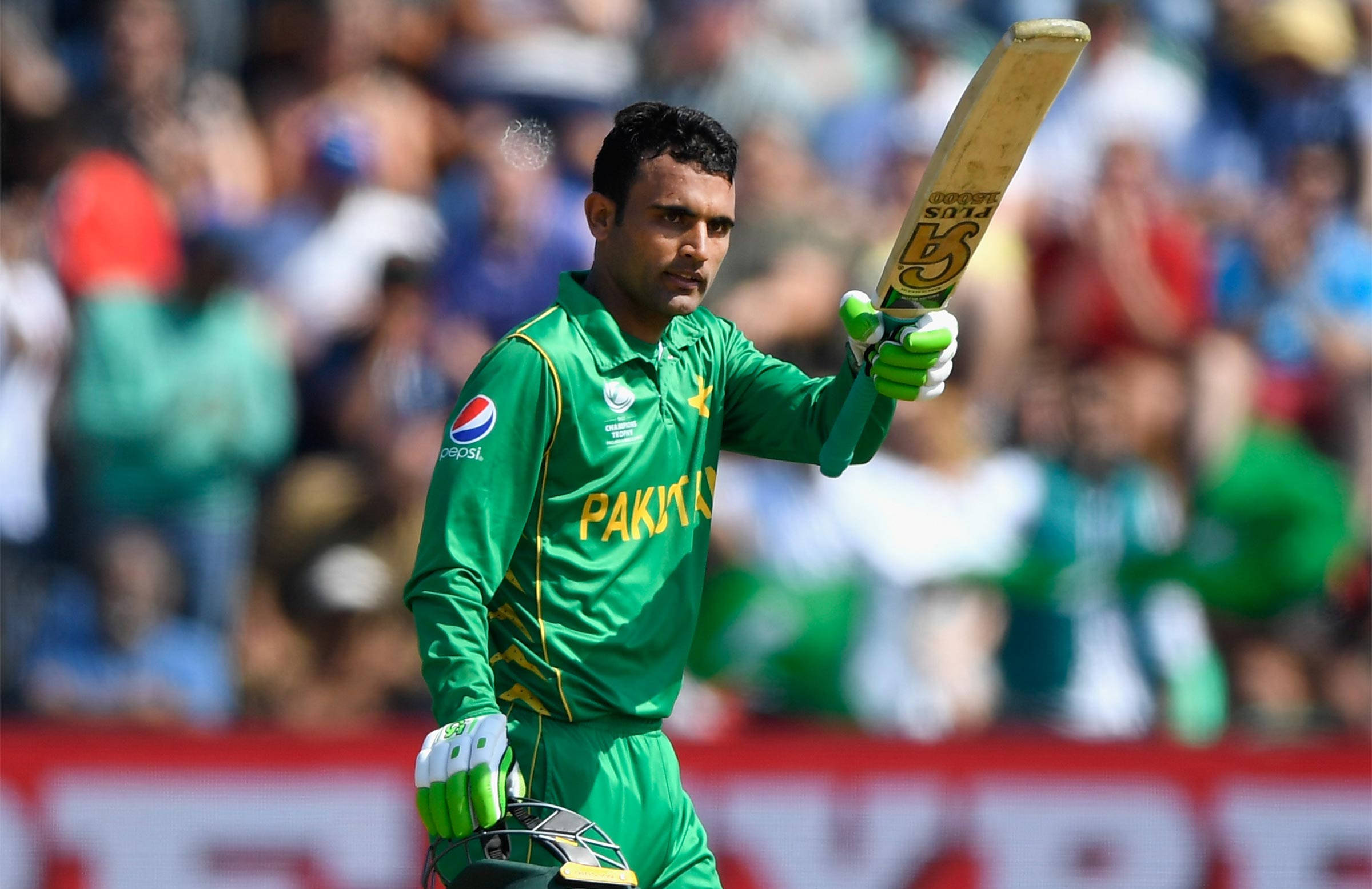 Fakhar Zaman 桌布 壁紙 — 一名身穿綠色球衣的巴基斯坦板球運動員在日間比賽中，在歡呼的人群面前堅定地高舉球棒。