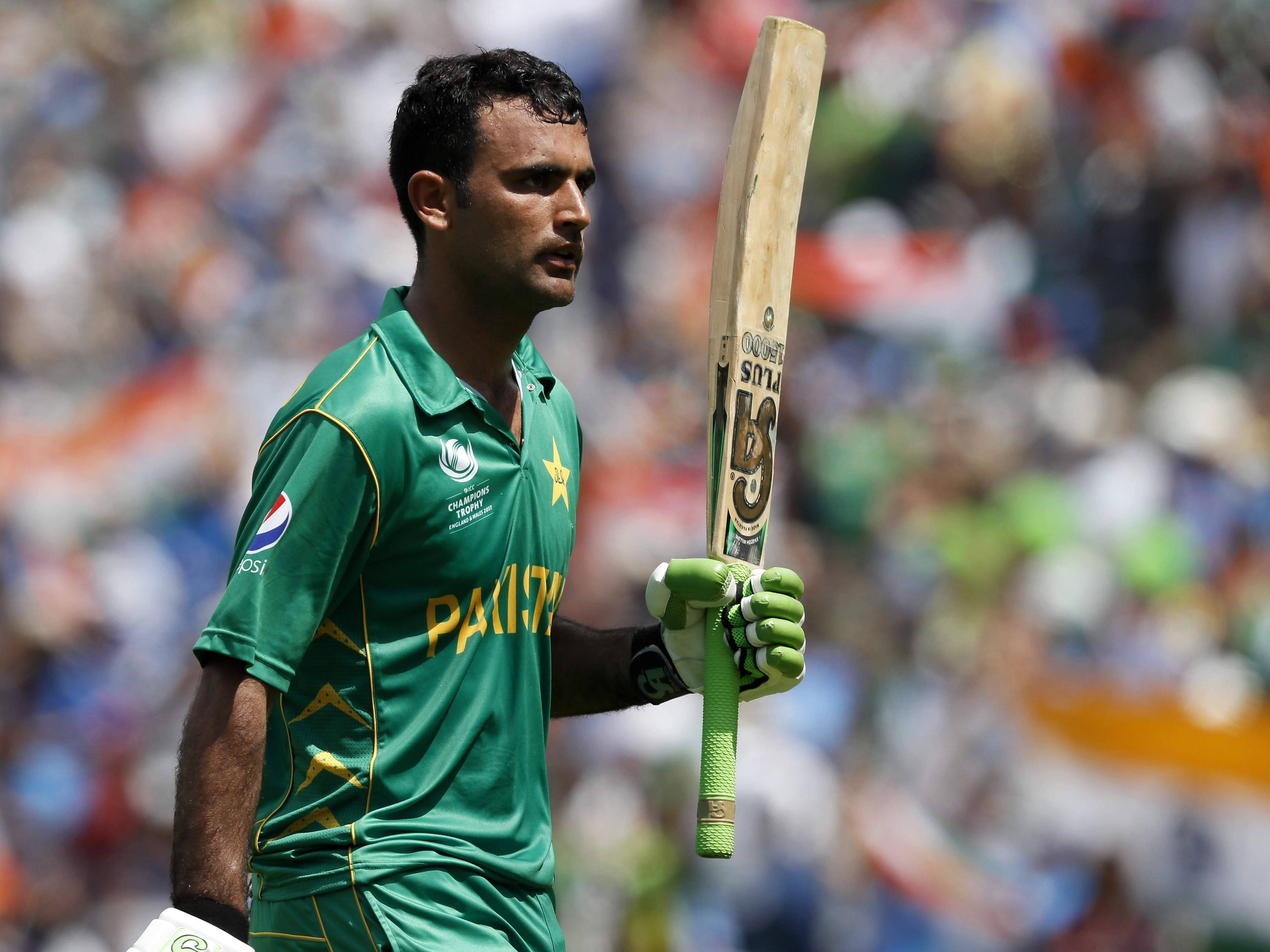 Fakhar Zaman 桌布 壁紙 — 一名身穿綠色球衣的巴基斯坦板球運動員，在模糊的體育場人群背景下，手持球棒，神情專注。