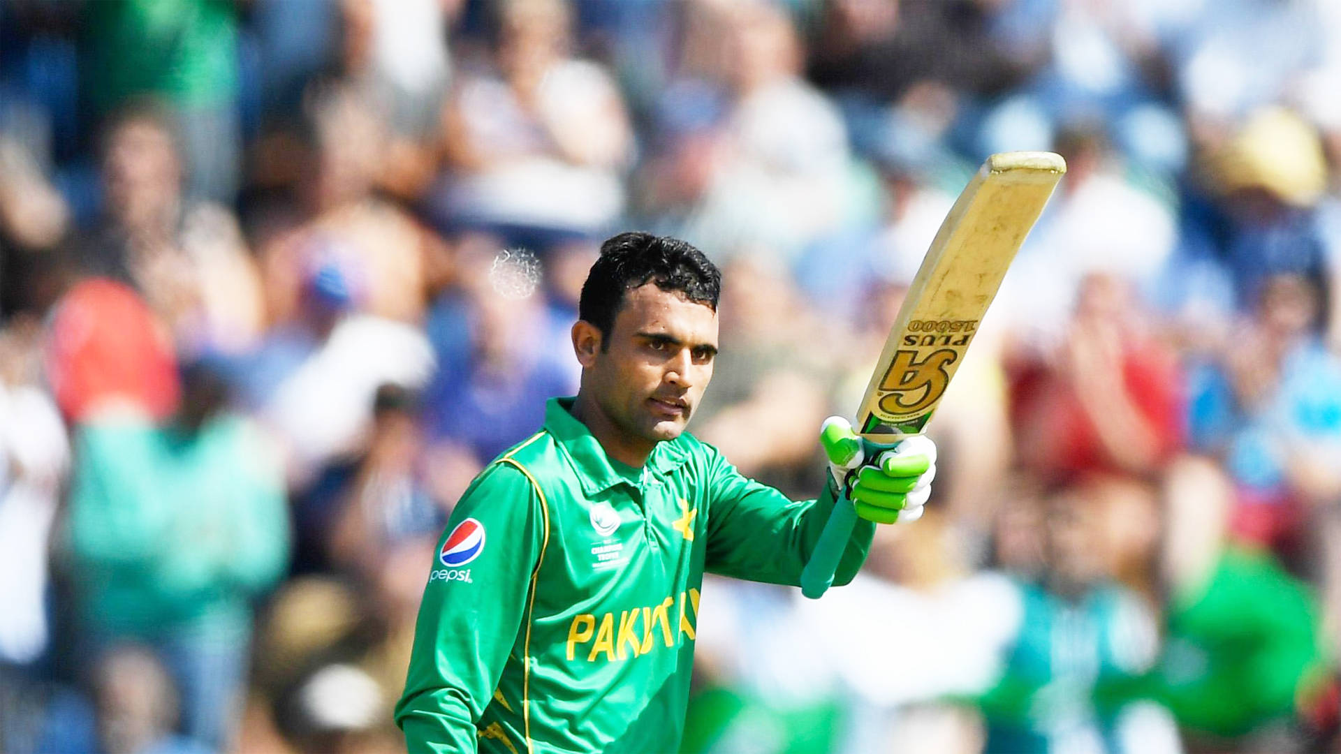 Fakhar Zaman 桌布 壁紙 — 一名身穿綠色球衣的巴基斯坦板球運動員在明亮的日光下，背景是模糊的觀眾，高舉球棒慶祝勝利。