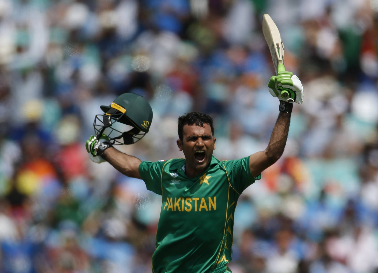 Fakhar Zaman 桌布 壁紙 — 一名身穿綠色球衣的巴基斯坦板球運動員在明亮的日光下，在歡呼的人群中勝利地高舉球棒和頭盔。