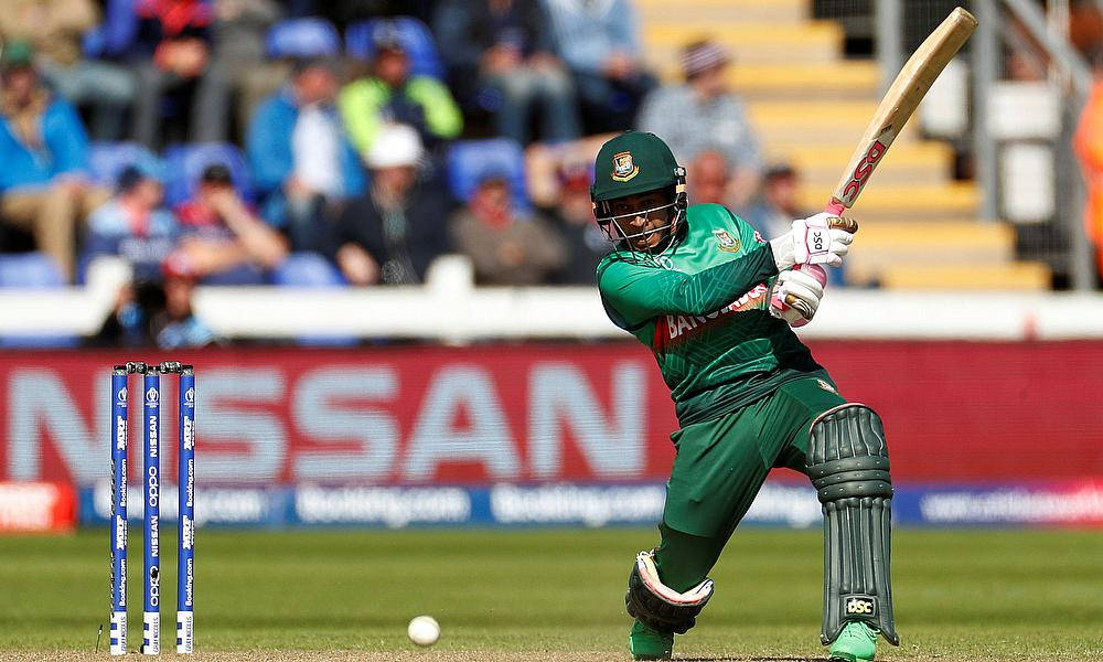 Bangladesh Cricket 桌布 壁紙 — 一名身穿綠色球衣的板球擊球手在日間比賽中，在觀眾背景下強力揮棒擊球。
