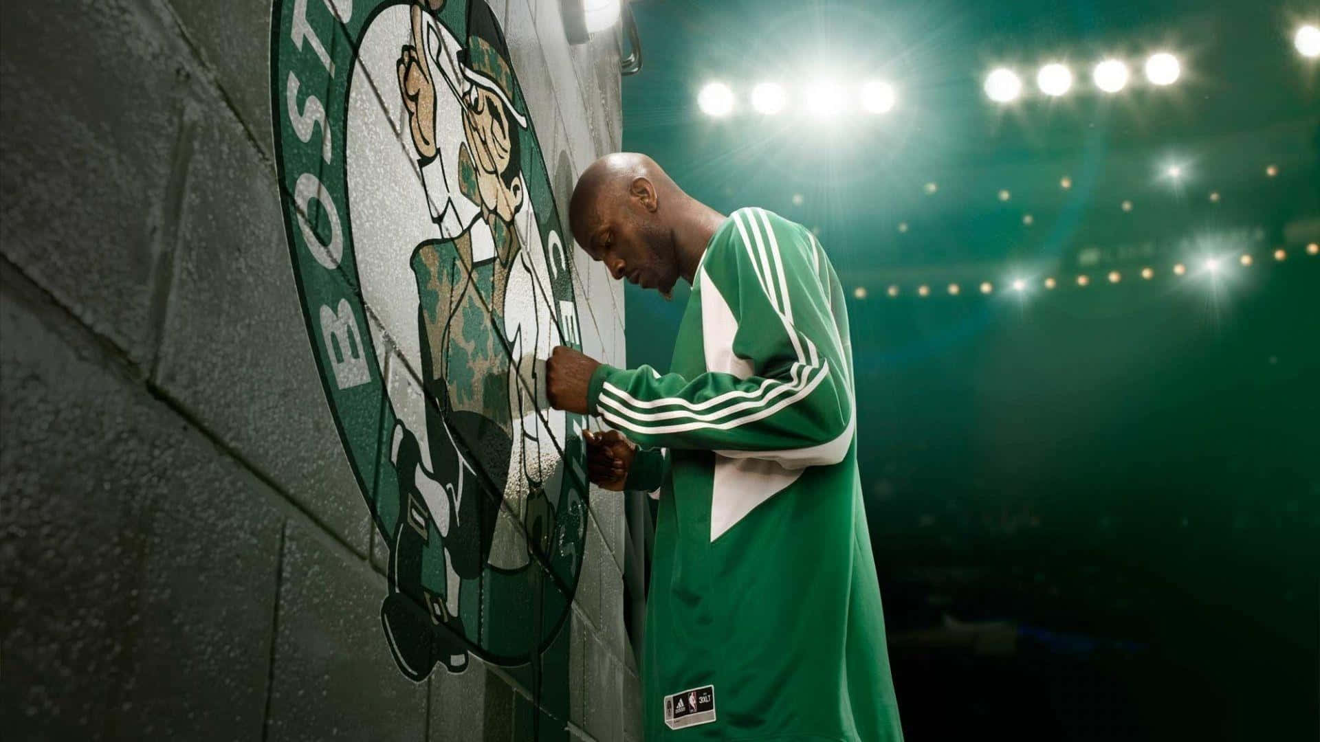 NBA Players 桌布 壁紙 — 一名身穿綠色球衣的籃球運動員在明亮的場館燈光下觸摸磚牆上的波士頓塞爾提克標誌。