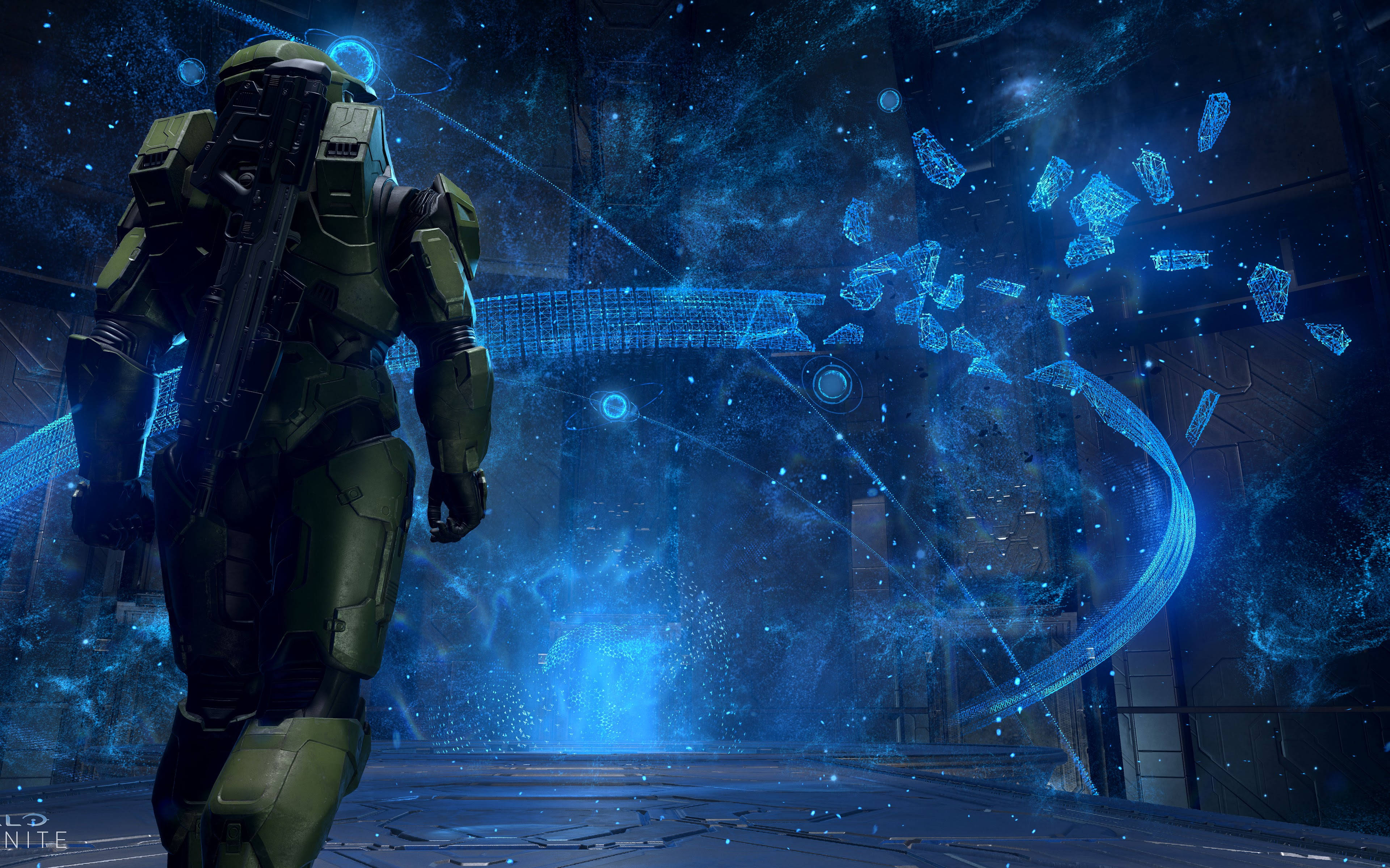 Halo Infinite 4K 桌布 壁紙 — 一名身穿綠色盔甲的士兵站在未來科幻場景中發光的藍色全息介面前。