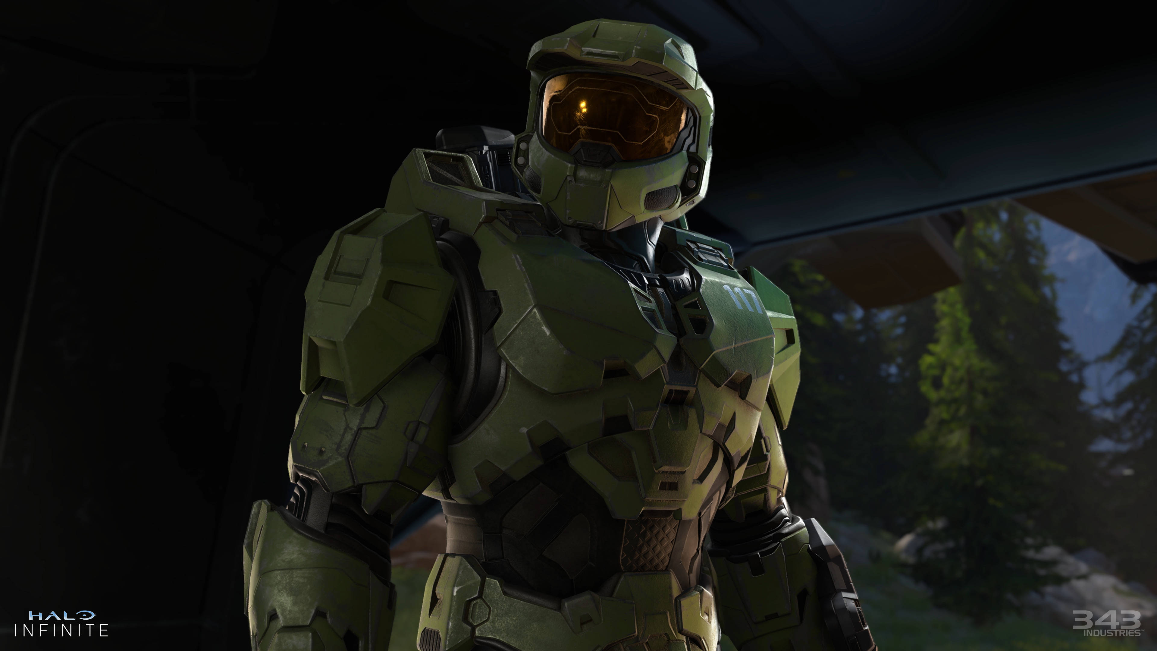 4K halo 桌布 壁紙 — 一名身穿綠色裝甲服、戴著發光橙色面罩的士兵站在車輛內，俯瞰著森林覆蓋的山地景觀。