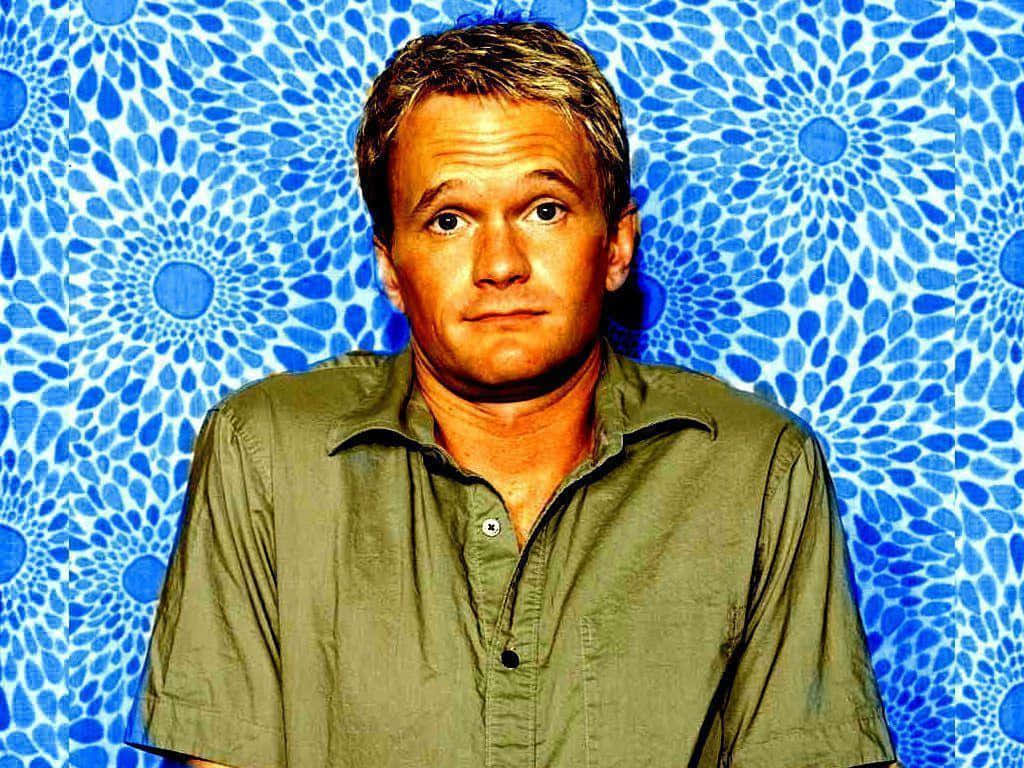 neil patrick harris 桌布 壁紙 — 一名身穿綠色襯衫的男子站在帶有圓形花卉圖案的鮮豔藍色圖案背景前。