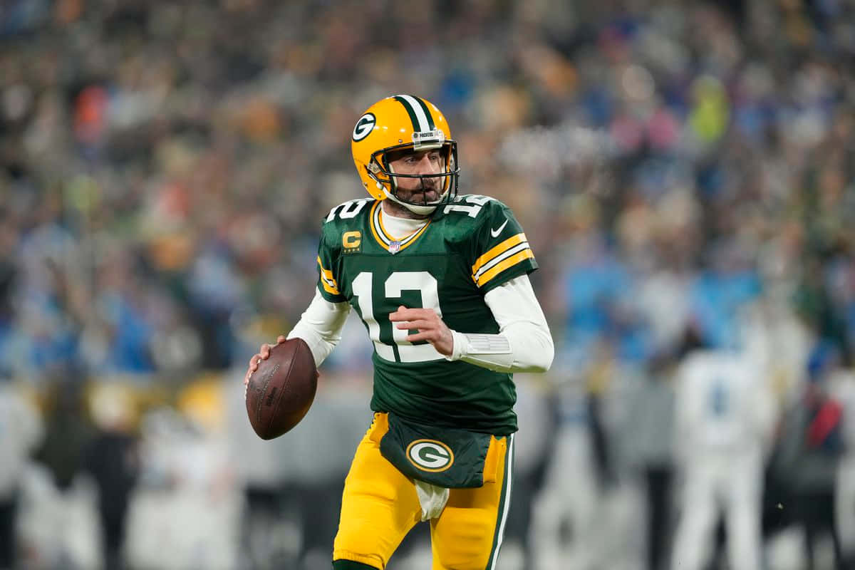 Aaron Rodgers 桌布 壁紙 — 一名身穿綠金色球衣的綠灣包裝工四分衛在夜間比賽的球場燈光下準備傳球。