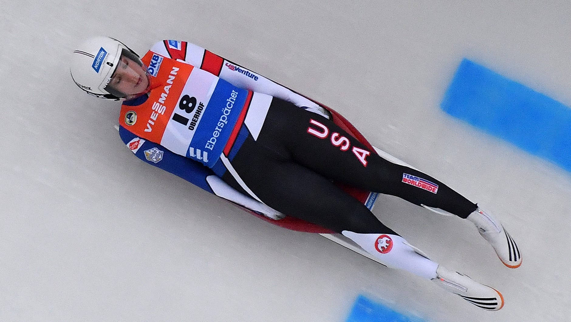 Olympics 桌布 壁紙 — 一名身穿美國裝備的雪橇運動員，以極度專注和高速在冰道上飛馳。