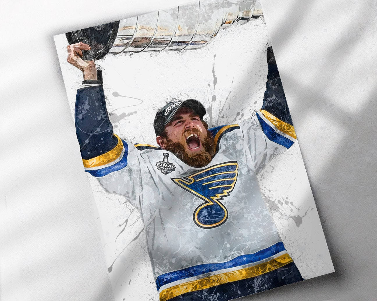 hockey 桌布 壁紙 — 一名身穿聖路易斯藍調球衣的冰球運動員，在白色潑濺背景上，以咆哮的表情勝利地高舉史丹利盃。