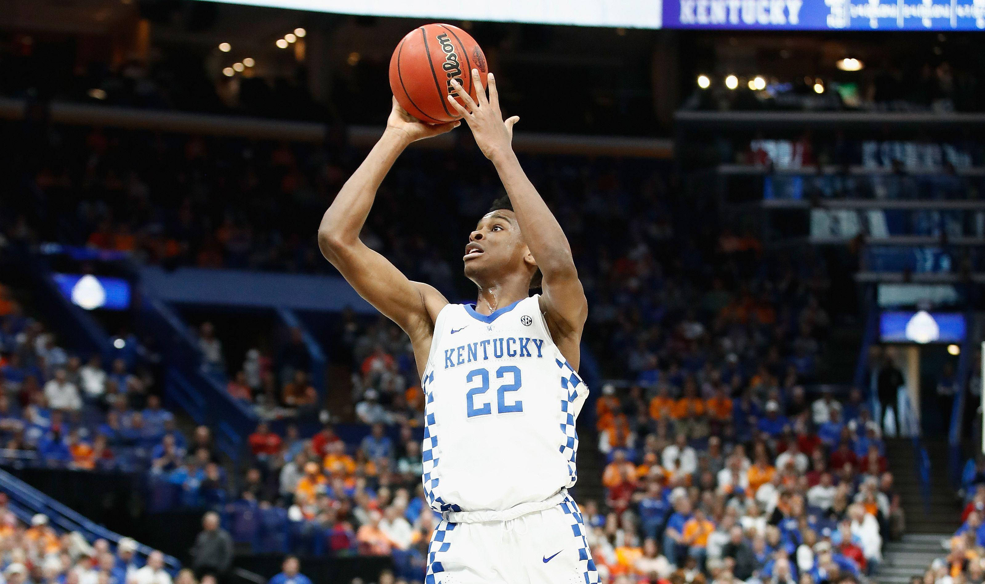 Shai Gilgeous Alexander 桌布 壁紙 — 一名身穿肯塔基球衣的籃球運動員在明亮的場館燈光下投罰球，背景是模糊的人群。