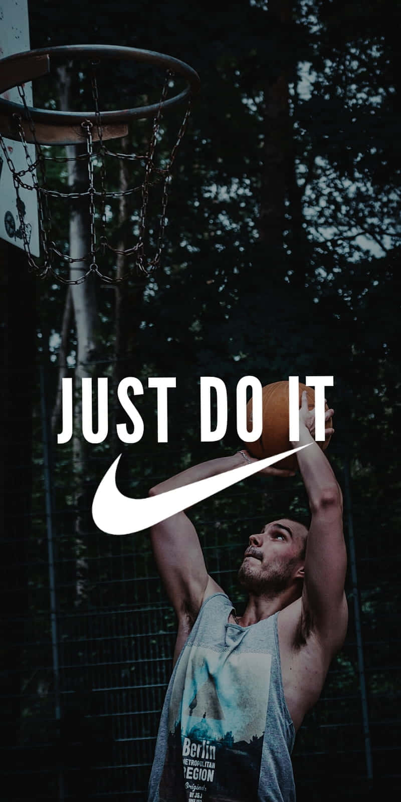 Nike 節奏籃球 桌布 壁紙 — 一名身穿背心的肌肉男在昏暗的森林球場上，將籃球灌入鏈條籃框，並帶有醒目的Nike品牌標誌。