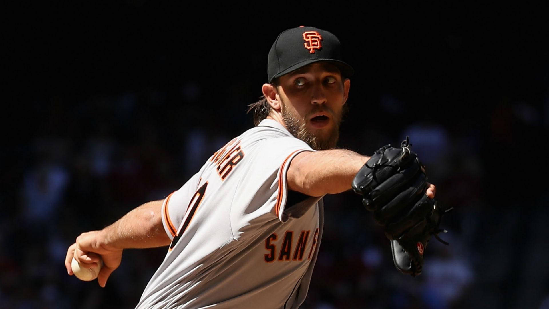 madison bumgarner 桌布 壁紙 — 一名身穿舊金山巨人隊球衣的棒球投手在明亮的球場燈光下，以高度專注力投出強力一球。