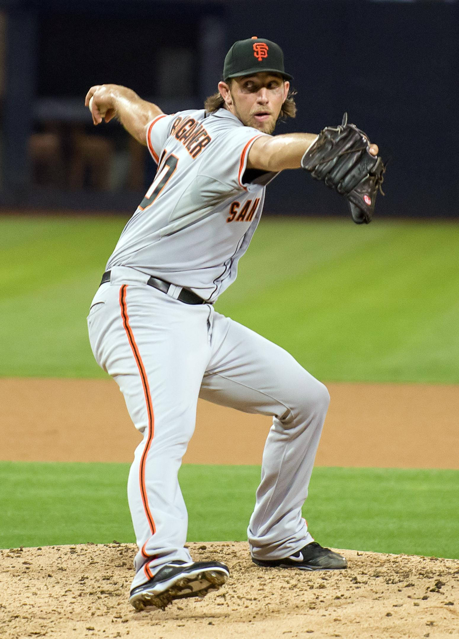 madison bumgarner 桌布 壁紙 — 一名身穿舊金山巨人隊球衣的棒球投手，在球場燈光下，於光線充足的投手丘上投球。