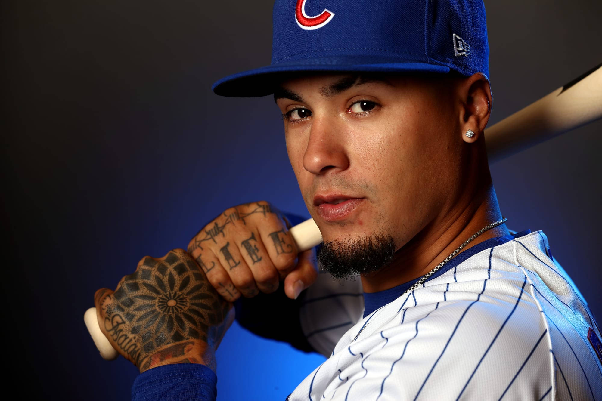 Baez 桌布 壁紙 — 一名身穿芝加哥小熊隊球衣的棒球選手，在深藍色攝影棚背景下，用有刺青的手握著球棒。