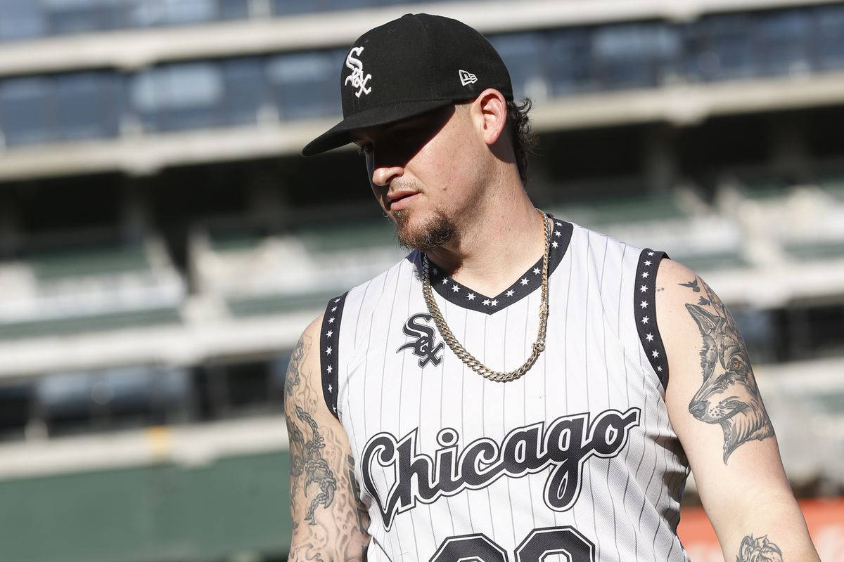Chicago White Sox 桌布 壁紙 — 一名身穿芝加哥白襪隊球衣、有刺青和戴帽子的棒球運動員，在明亮的日光下站在球場上。