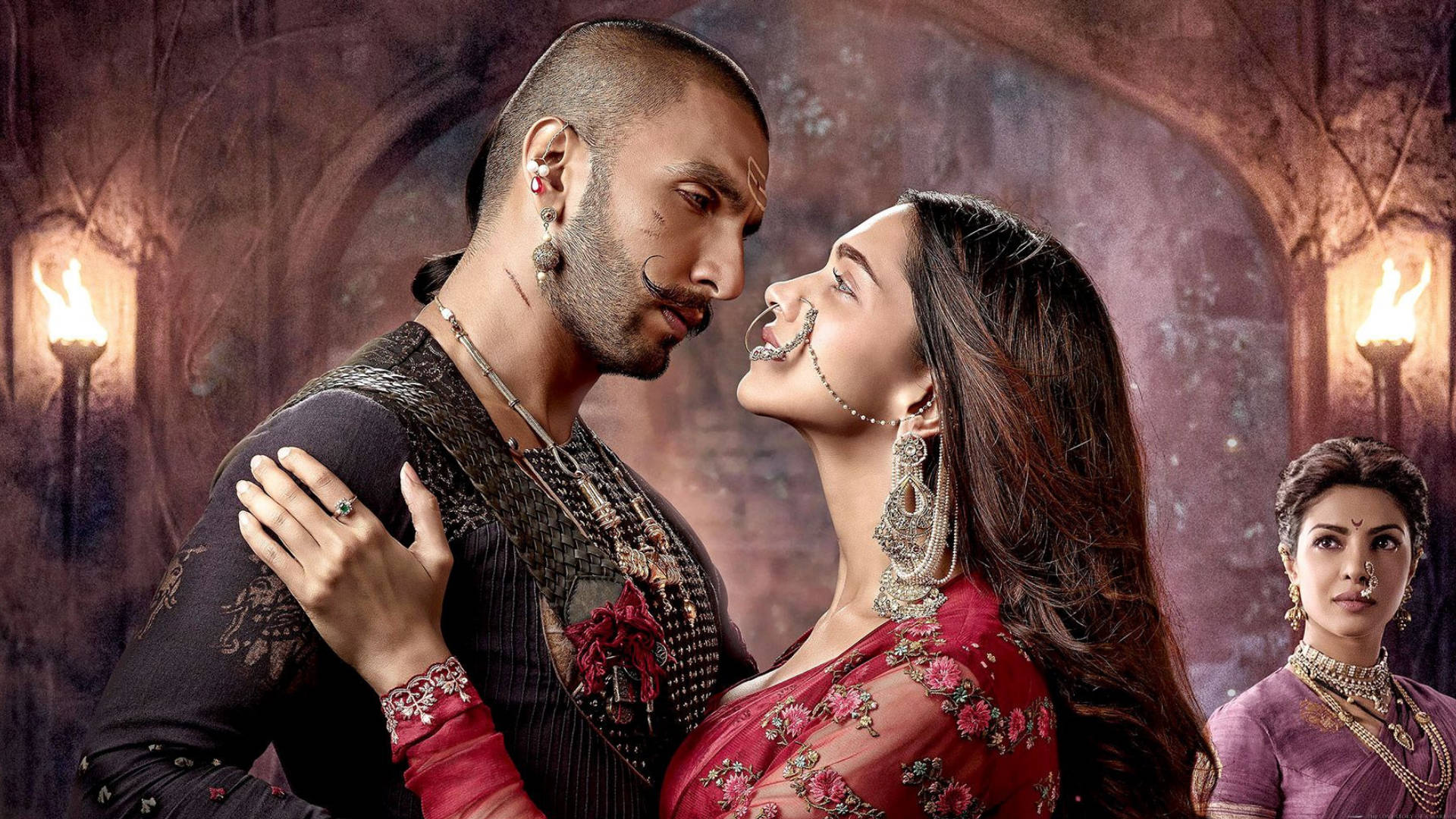 Ranveer Singh 桌布 壁紙 — 一名身穿華麗傳統服飾的男子和女子，在火炬照亮的昏暗哥德式拱廊中深情對望。