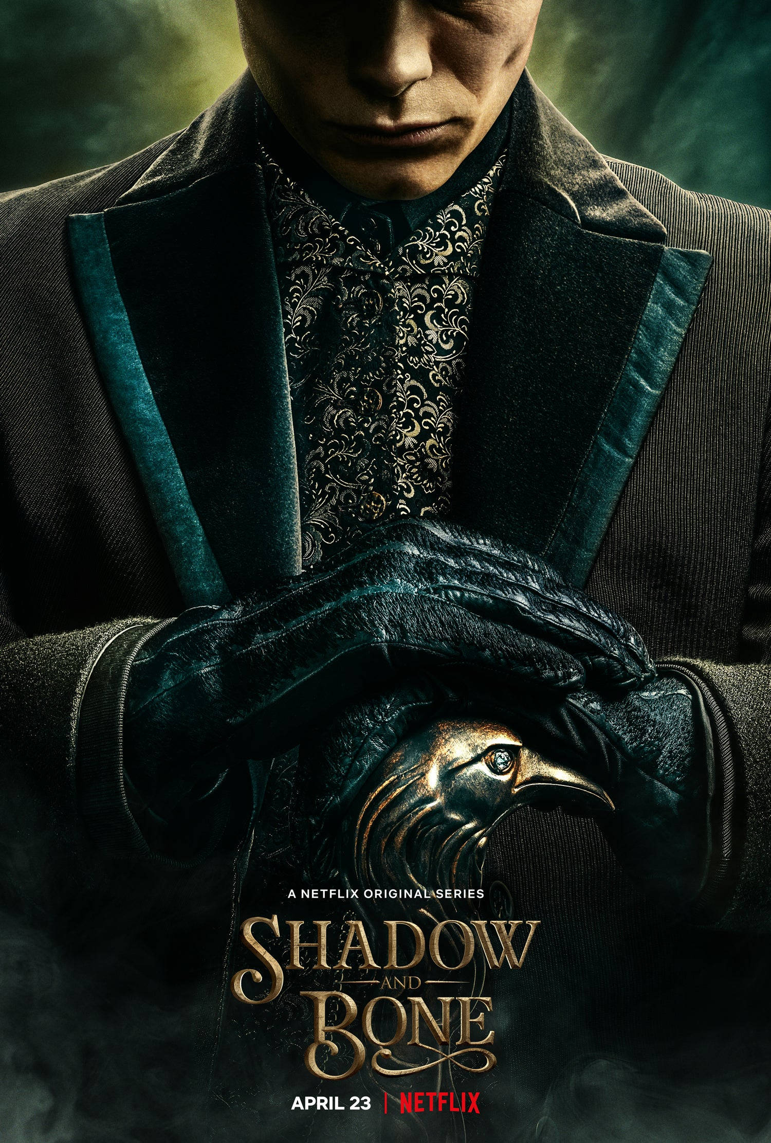 shadow 桌布 壁紙 — 一名身穿華麗深色衣服的男子，在煙霧瀰漫的綠色背景下，專注地拿著一個金屬鳥面具。