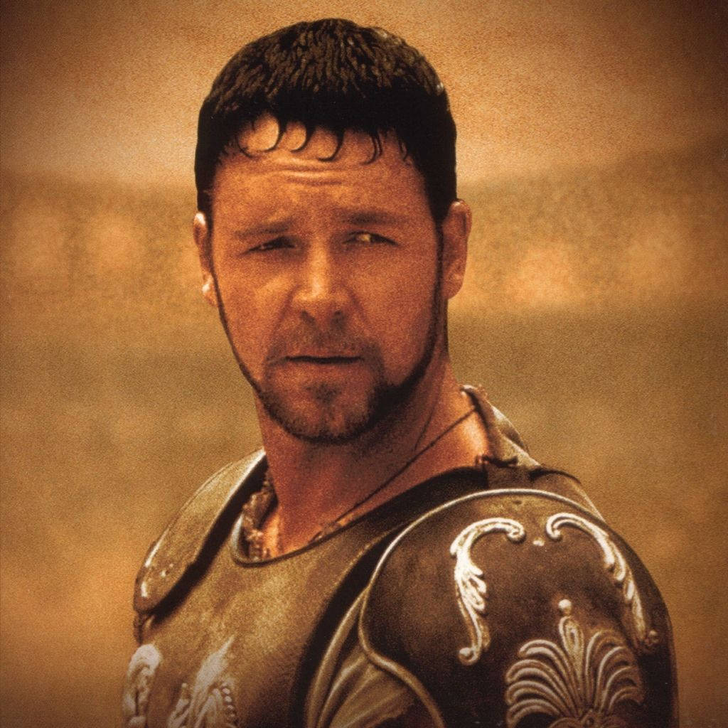 Gladiator 桌布 壁紙 — 一名身穿華麗盔甲、表情嚴肅的羅馬士兵特寫，背景是朦朧的金色。