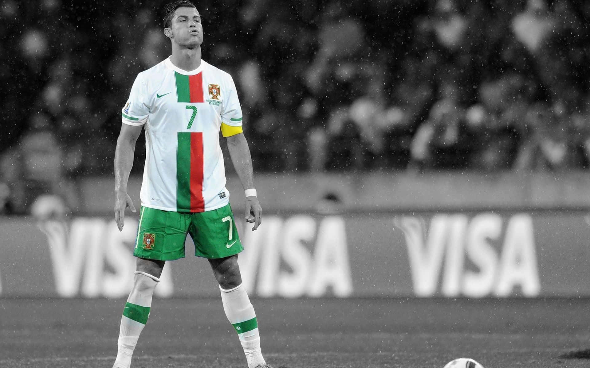 Ronaldo 桌布 壁紙 — 一名身穿葡萄牙球衣的足球員獨自站在雨中的球場上，身後是模糊的人群和VISA廣告。
