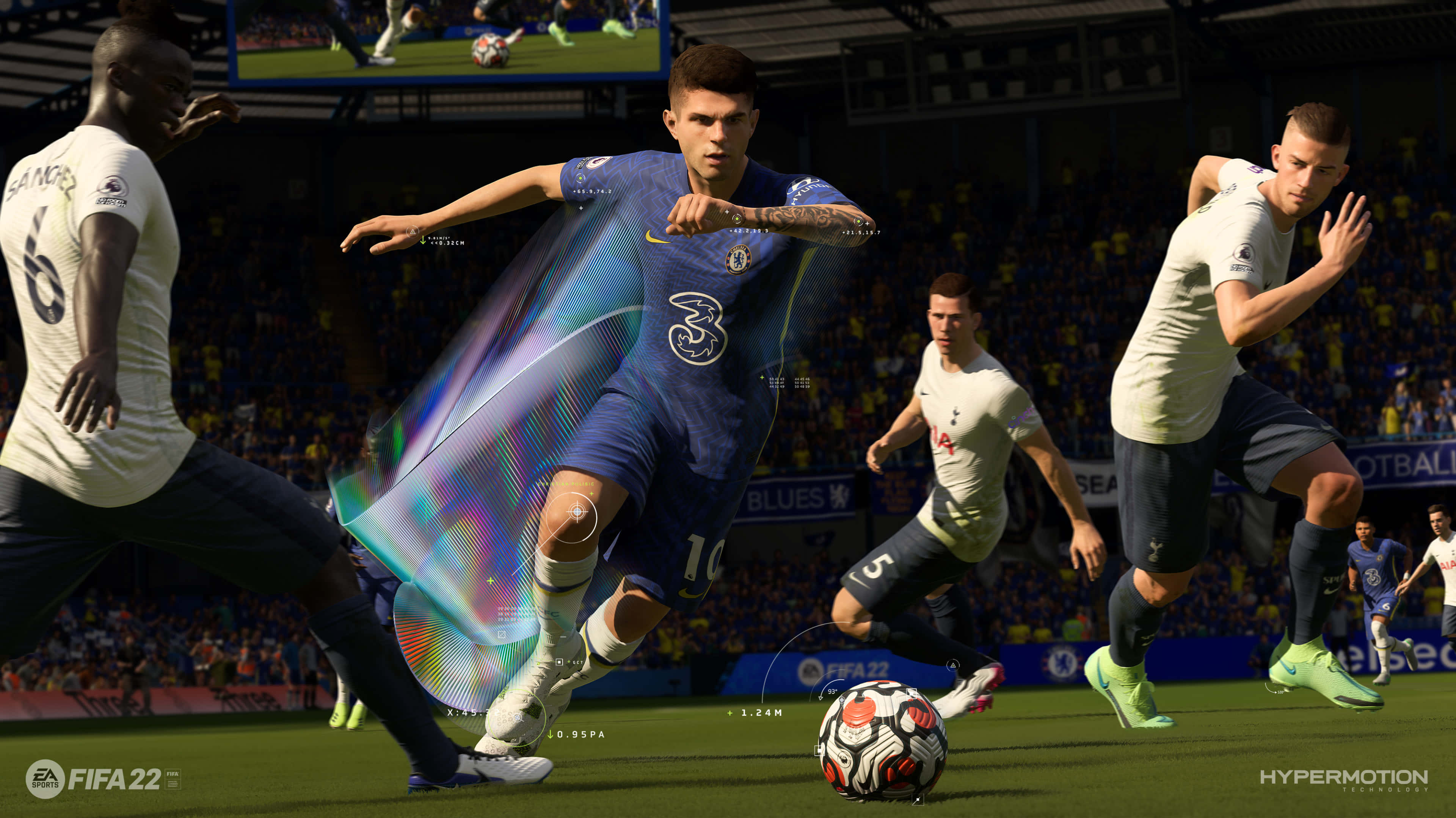 Fifa 22 桌布 壁紙 — 一名身穿蓝色球衣的足球运动员在座无虚席的体育场比赛中，用腿周围发光的彩虹效果运球。