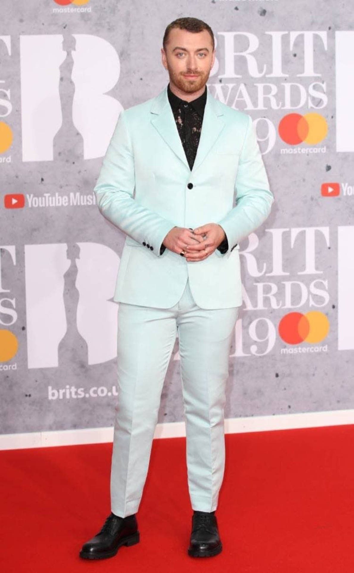 Sam Smith 桌布 壁紙 — 一名身穿薄荷綠色西裝的男子自信地站在2019年全英音樂獎的紅地毯上，身後有贊助商標誌。