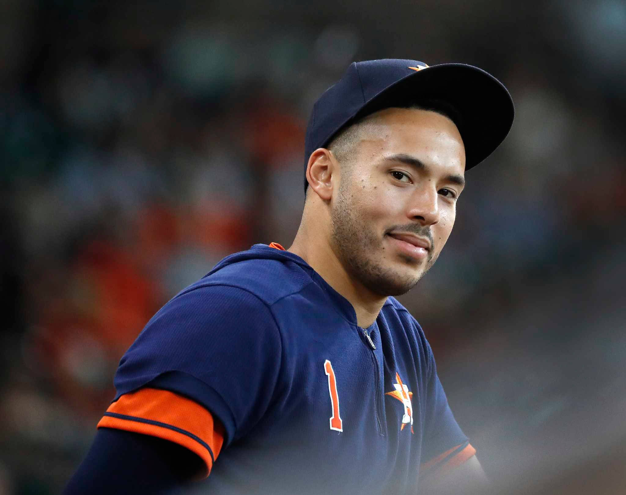 Carlos Correa 桌布 壁紙 — 一名身穿藍橙色球衣、背號1號的棒球運動員在比賽中戴著帽子輕輕微笑。
