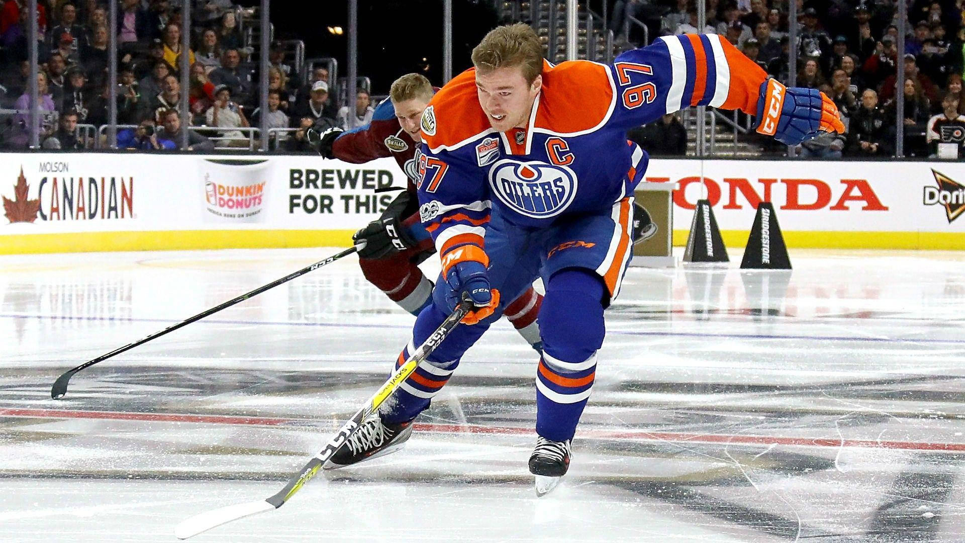 hockey 桌布 壁紙 — 一名身穿藍橙色球衣的愛德蒙頓油人冰球球員在冰上與身穿紅色的對手爭奪球權。