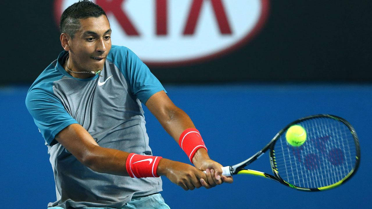 Kyrgios 桌布 壁紙 — 一名身穿藍灰色裝備的男網球選手在激烈的比賽中揮動球拍擊打亮黃色的球。