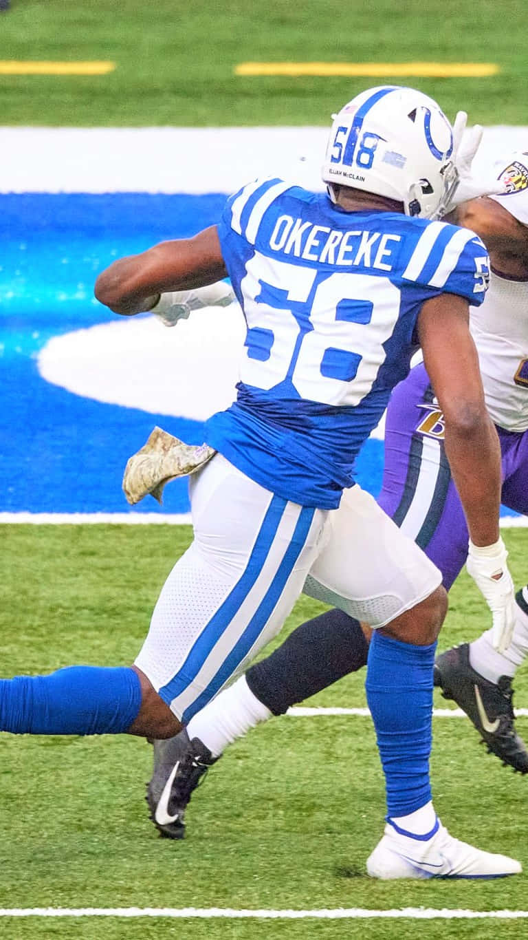Bobby Okereke 桌布 壁紙 — 一名身穿藍白球衣、號碼58的足球員在比賽期間於綠色球場上強力奔跑。