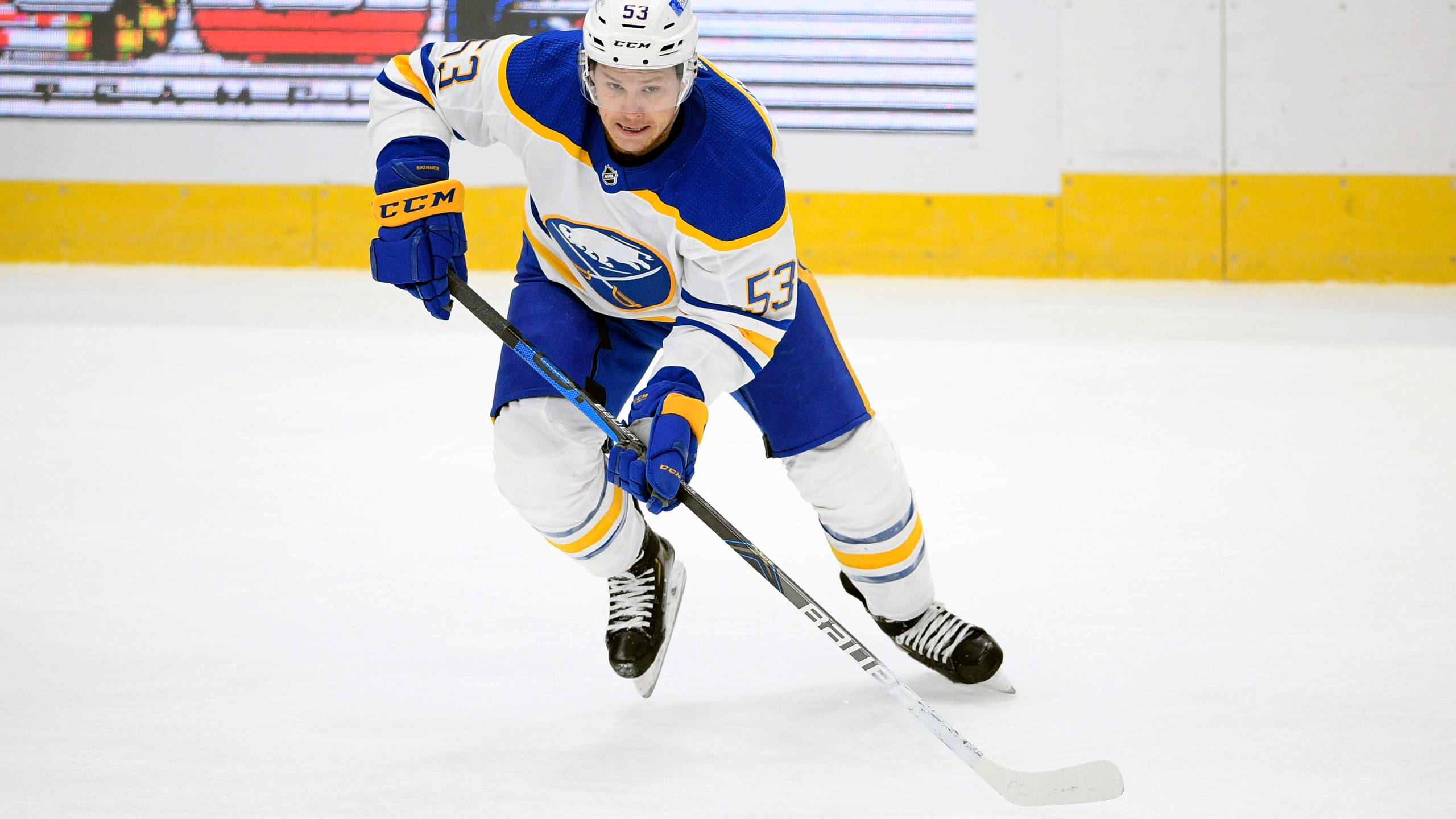 hockey 桌布 壁紙 — 一名身穿藍白球衣的冰球運動員在比賽中專注地向前滑行在冰面上。