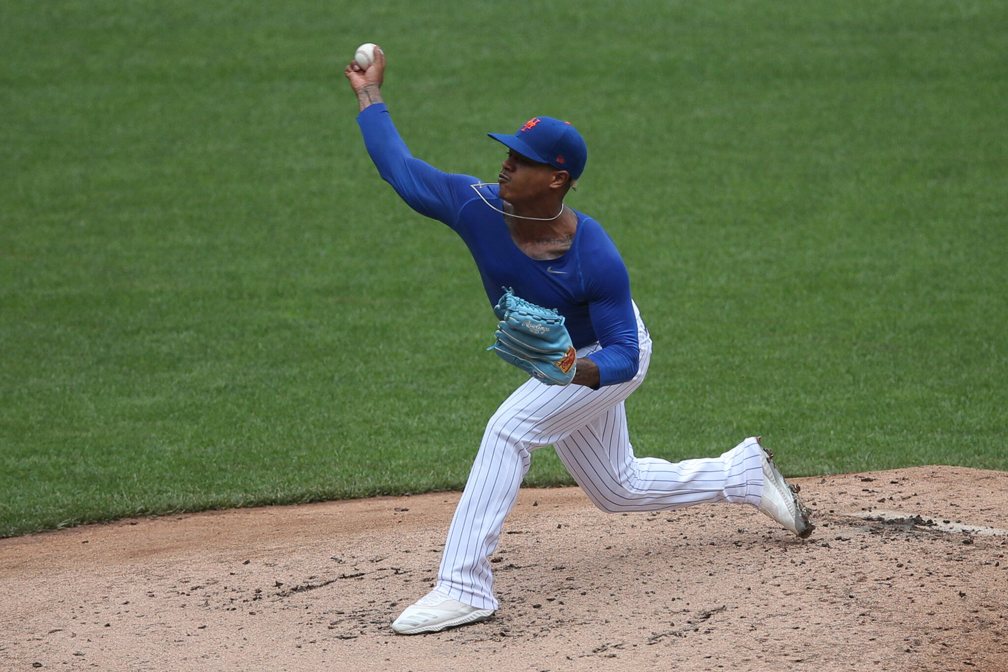 Marcus Stroman 桌布 壁紙 — 一名身穿藍白球衣的棒球投手在陽光明媚的場地上投球，場地有綠色草地和棕色泥土。