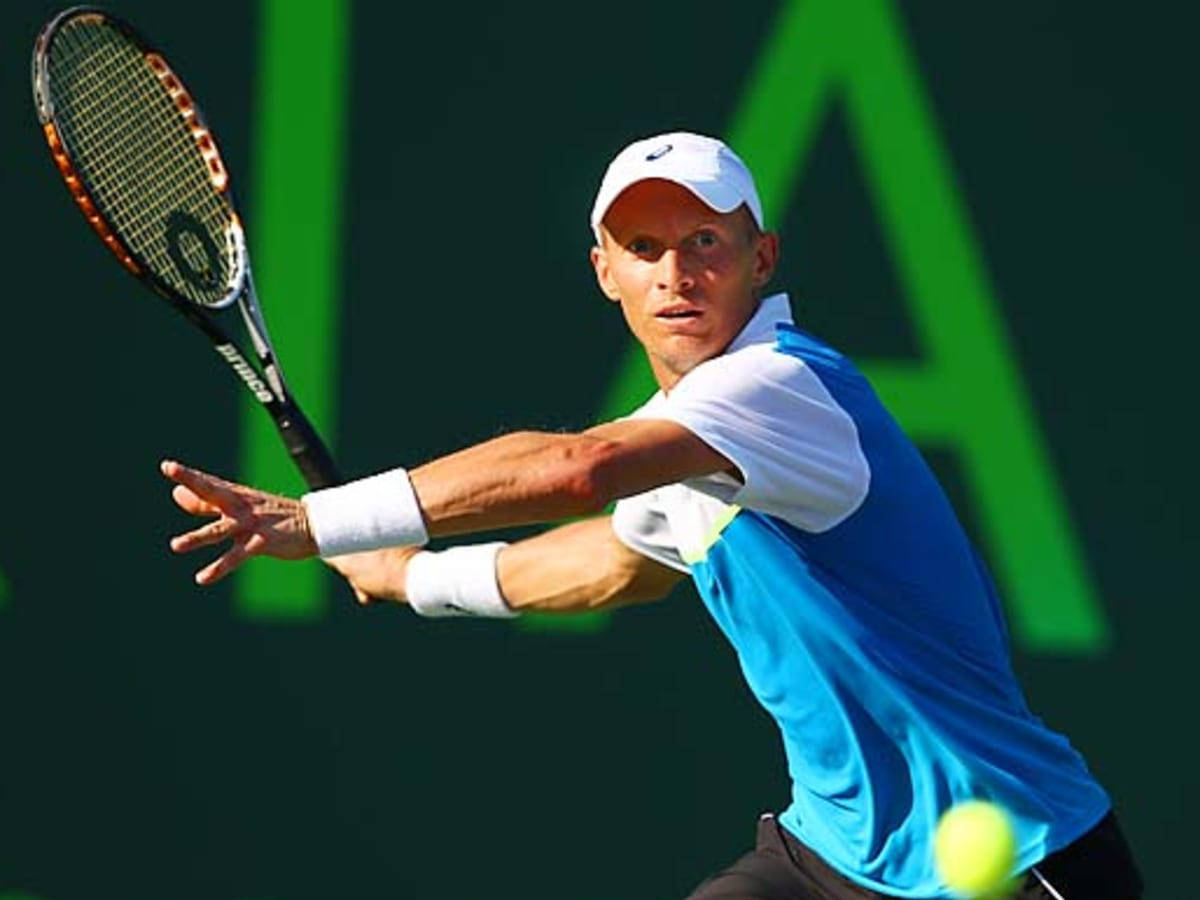 Tennis 桌布 壁紙 — 一名身穿藍白色裝備的男性網球選手，在深綠色背景上有一個大綠色字母的情況下，揮拍擊打一個黃色球。
