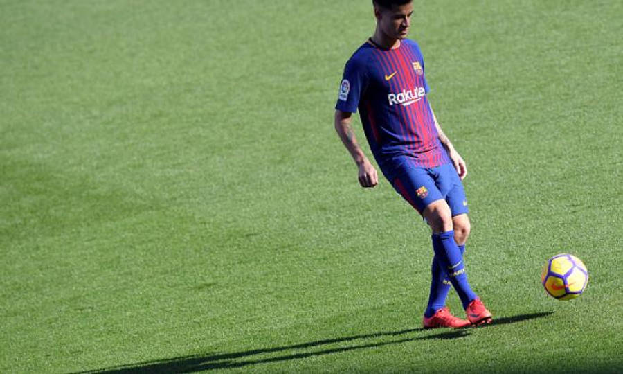 Philippe Coutinho 桌布 壁紙 — 一名身穿藍紅條紋球衣的足球運動員在燦爛陽光下，於充滿活力的綠色球場上控制著一個色彩繽紛的足球。