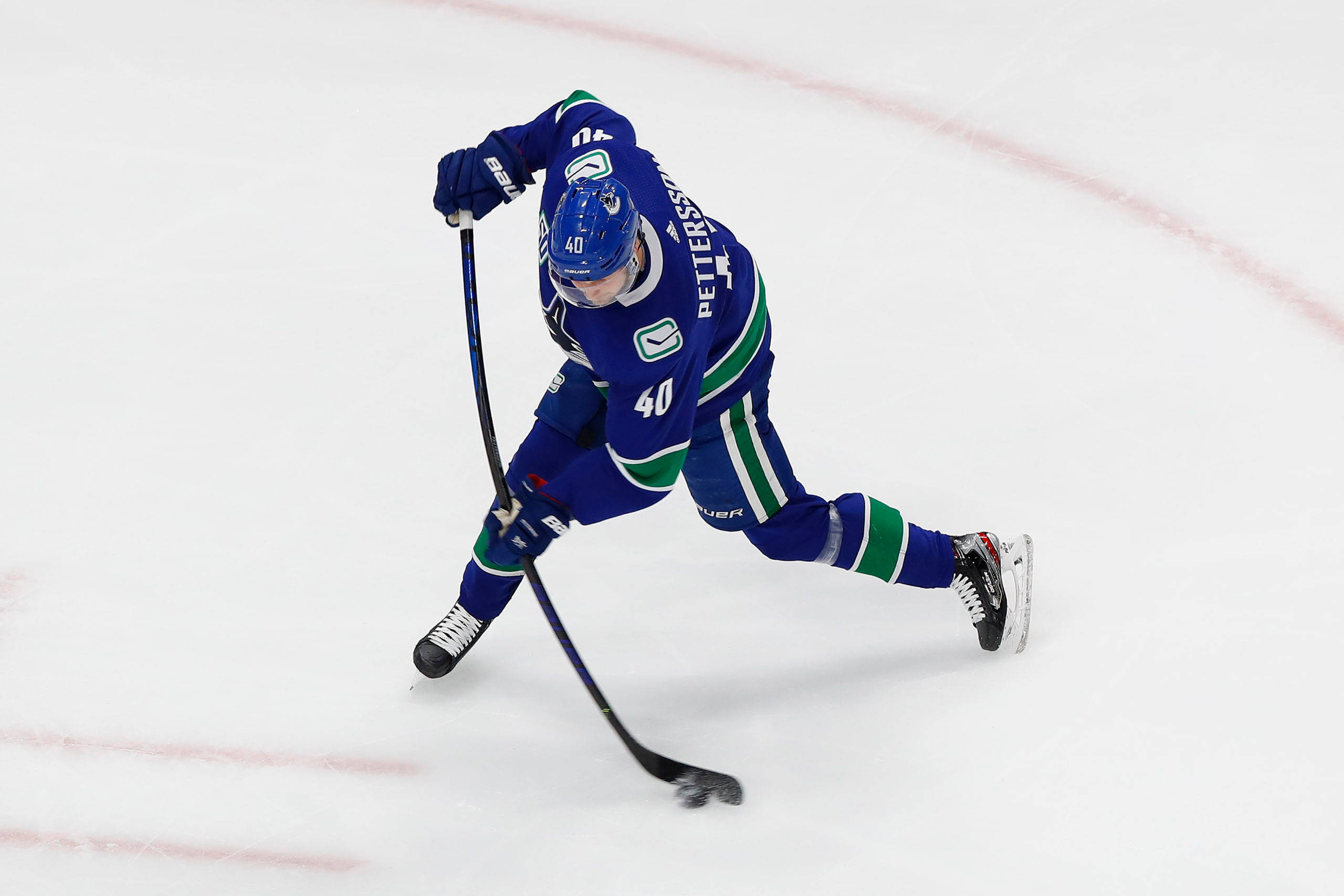 hockey 桌布 壁紙 — 一名身穿藍綠球衣的冰上曲棍球運動員在比賽中低身俯在冰上，手持球棍。