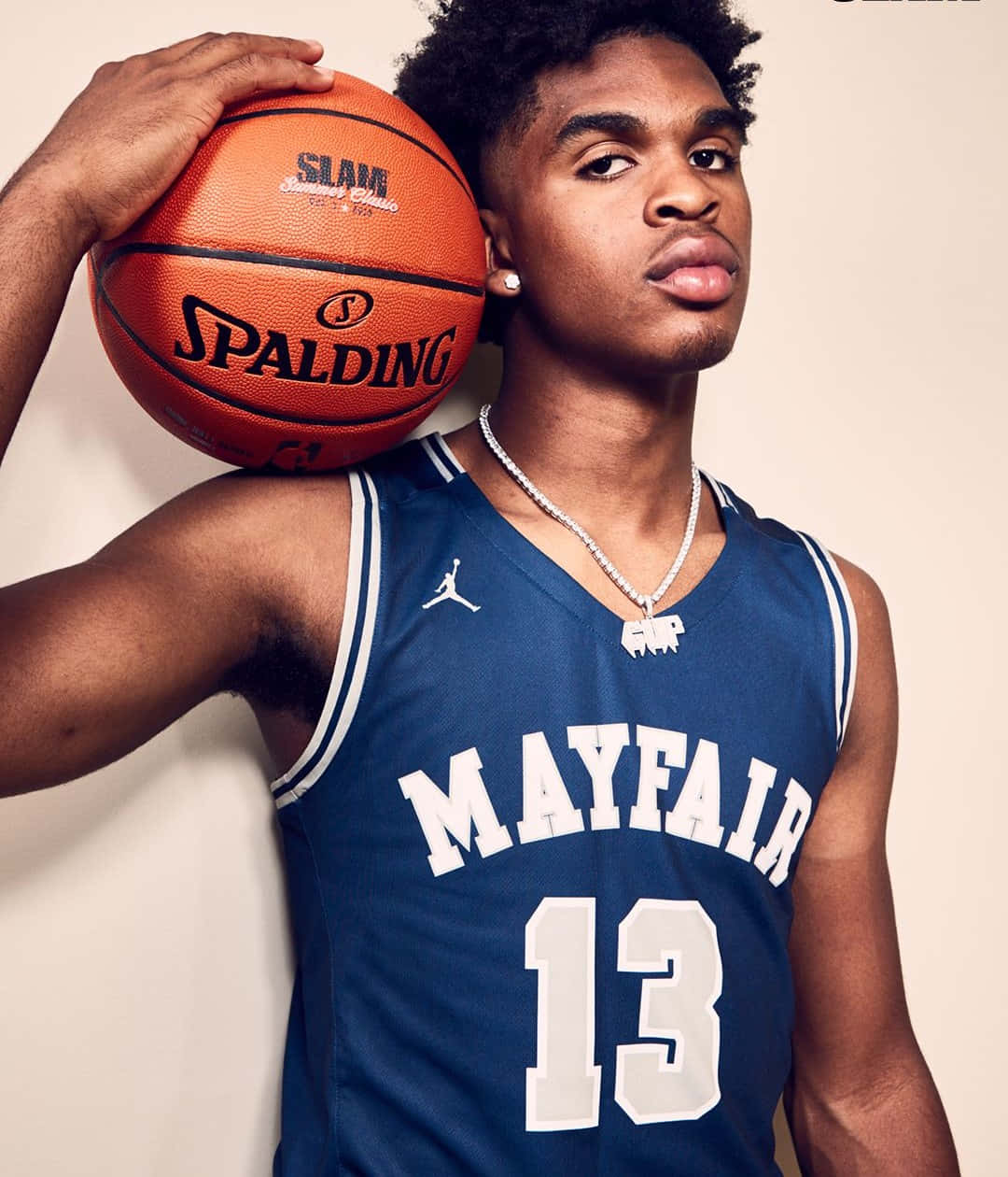 Jalen Green 桌布 壁紙 — 一名身穿藍色 Mayfair 球衣的年輕籃球運動員自信地拿著 Spalding 球，對著純米色牆壁擺姿勢。