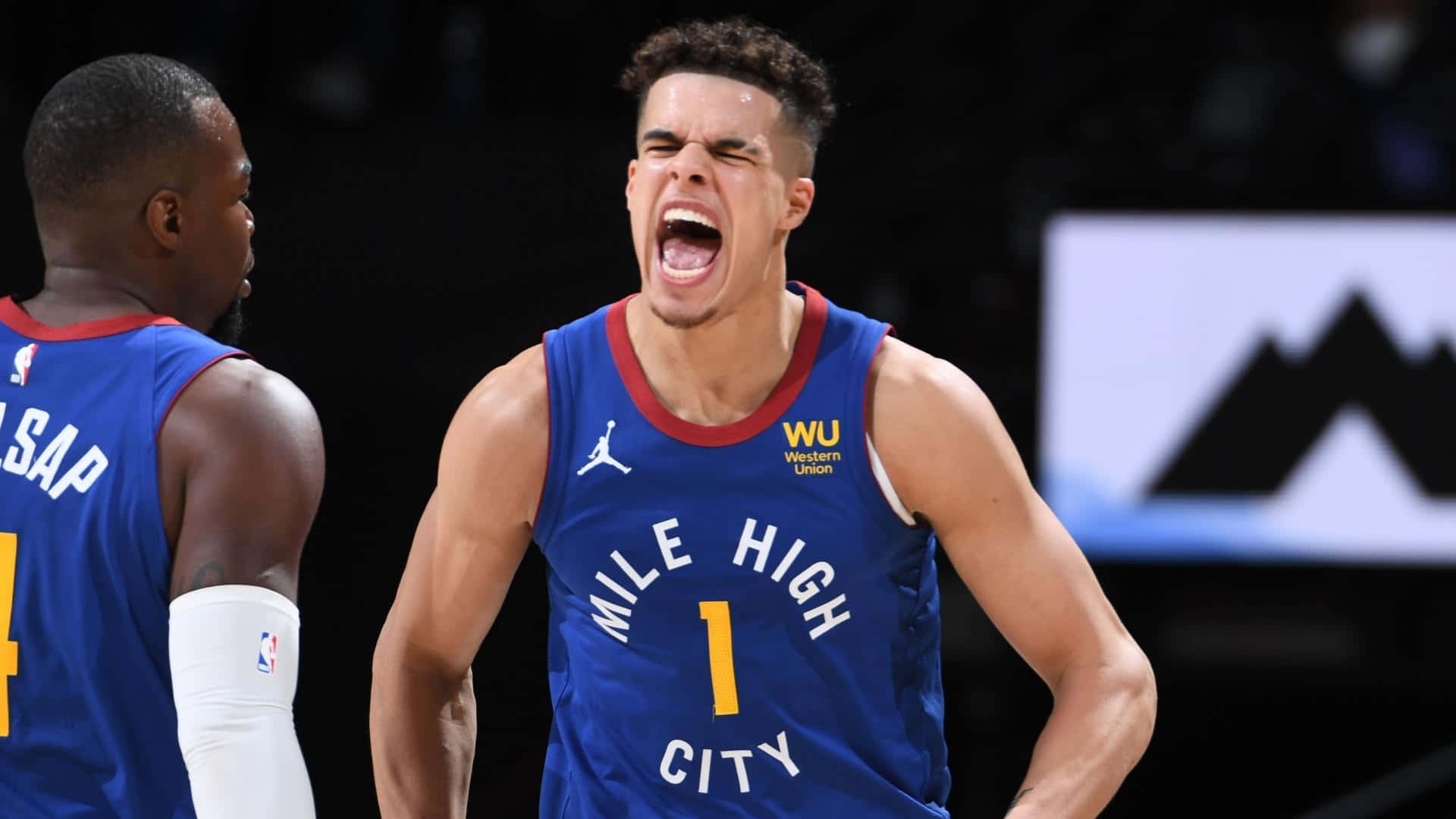 籃球 桌布 壁紙 — 一名身穿藍色「Mile High City」球衣的籃球運動員在比賽中熱情地吶喊，隊友在旁觀看。