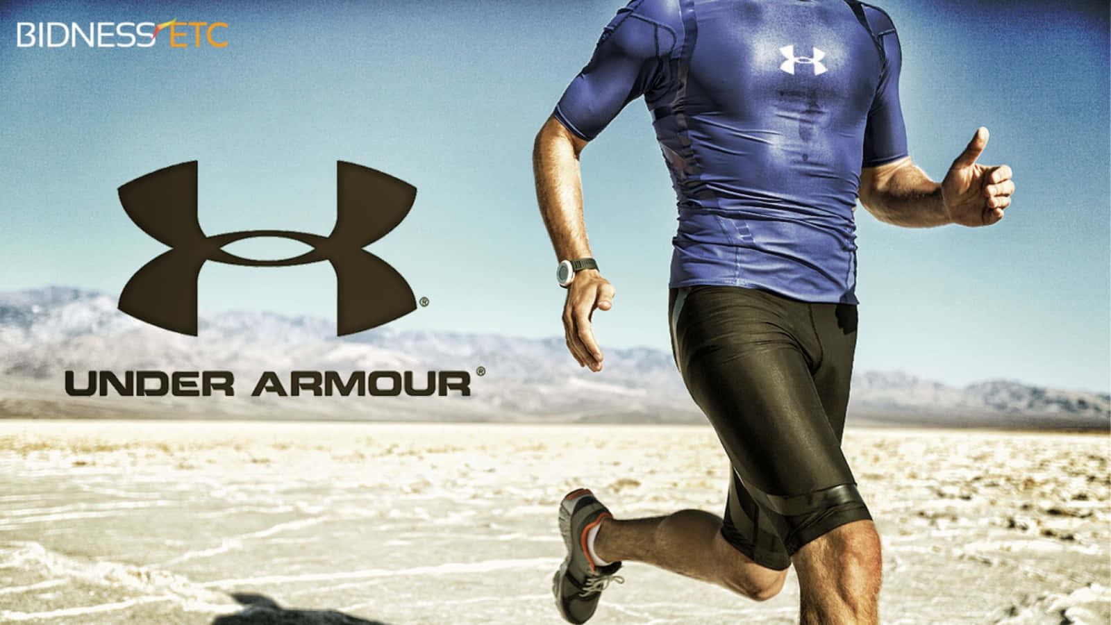 Under Armour 桌布 壁紙 — 一名身穿藍色 Under Armour 裝備的男子在陽光明媚的沙漠中奔跑，背景有山脈。