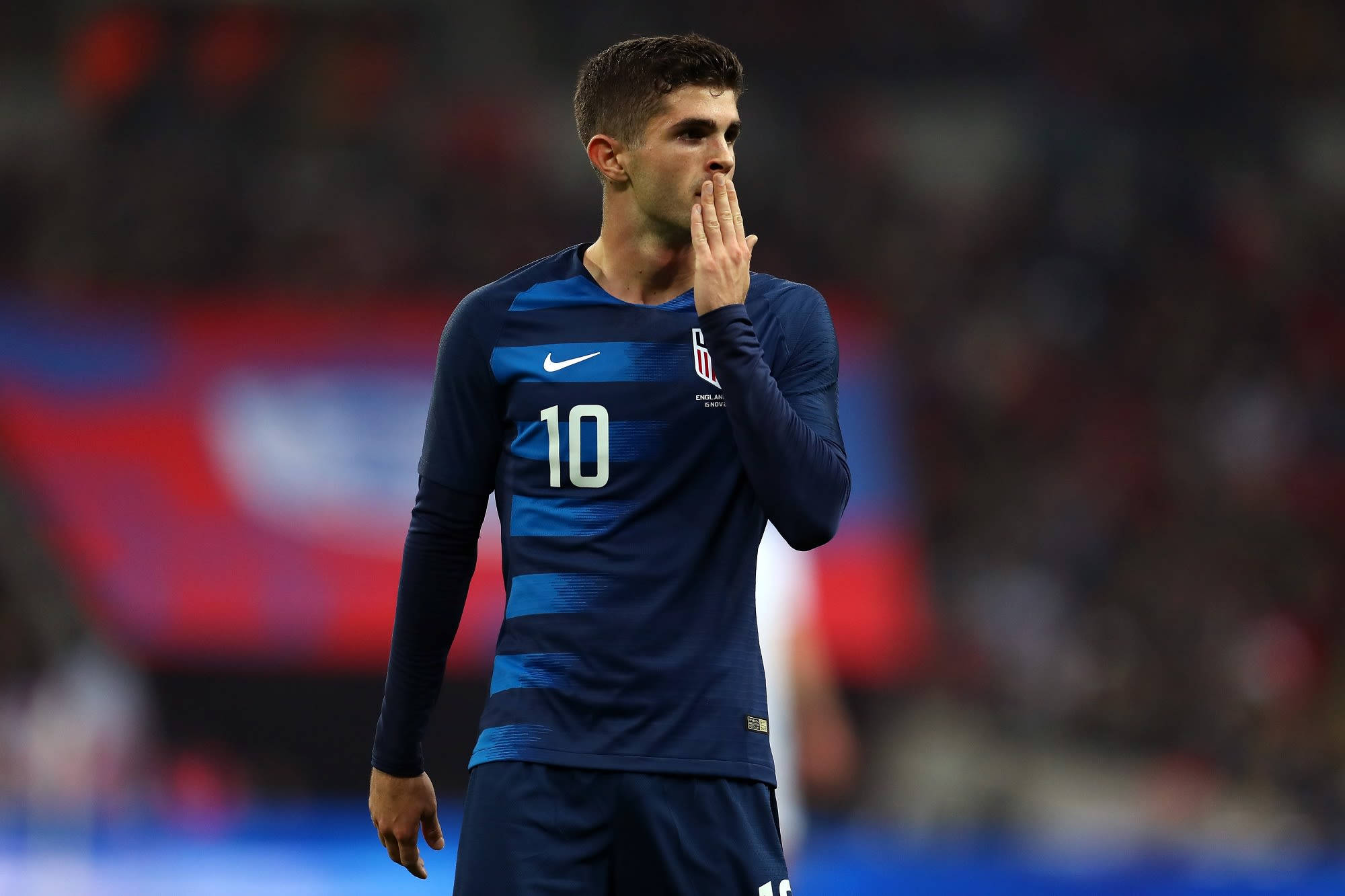 足球 桌布 壁紙 — 一名身穿藍色10號球衣的足球員站在球場上，用手摀住嘴巴。