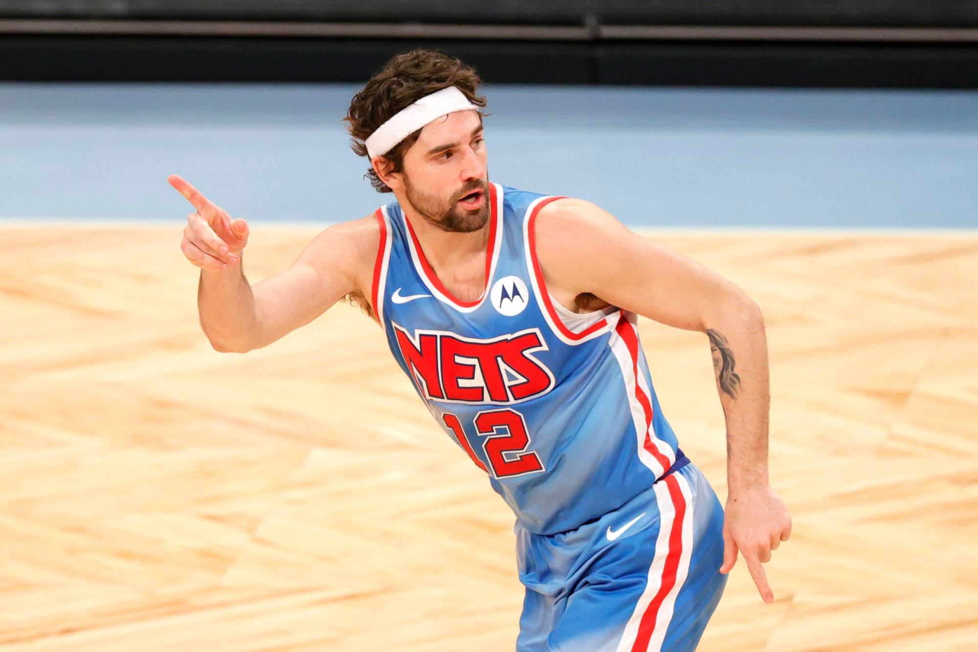 joe harris 桌布 壁紙 — 一名身穿藍色Nets球衣、背號12的籃球運動員在木地板上比賽時向前指。