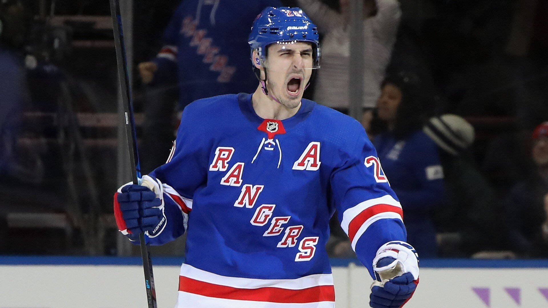 New 桌布 壁紙 — 一名身穿藍色Rangers球衣的冰上曲棍球運動員在冰上握著球棍勝利地吶喊。
