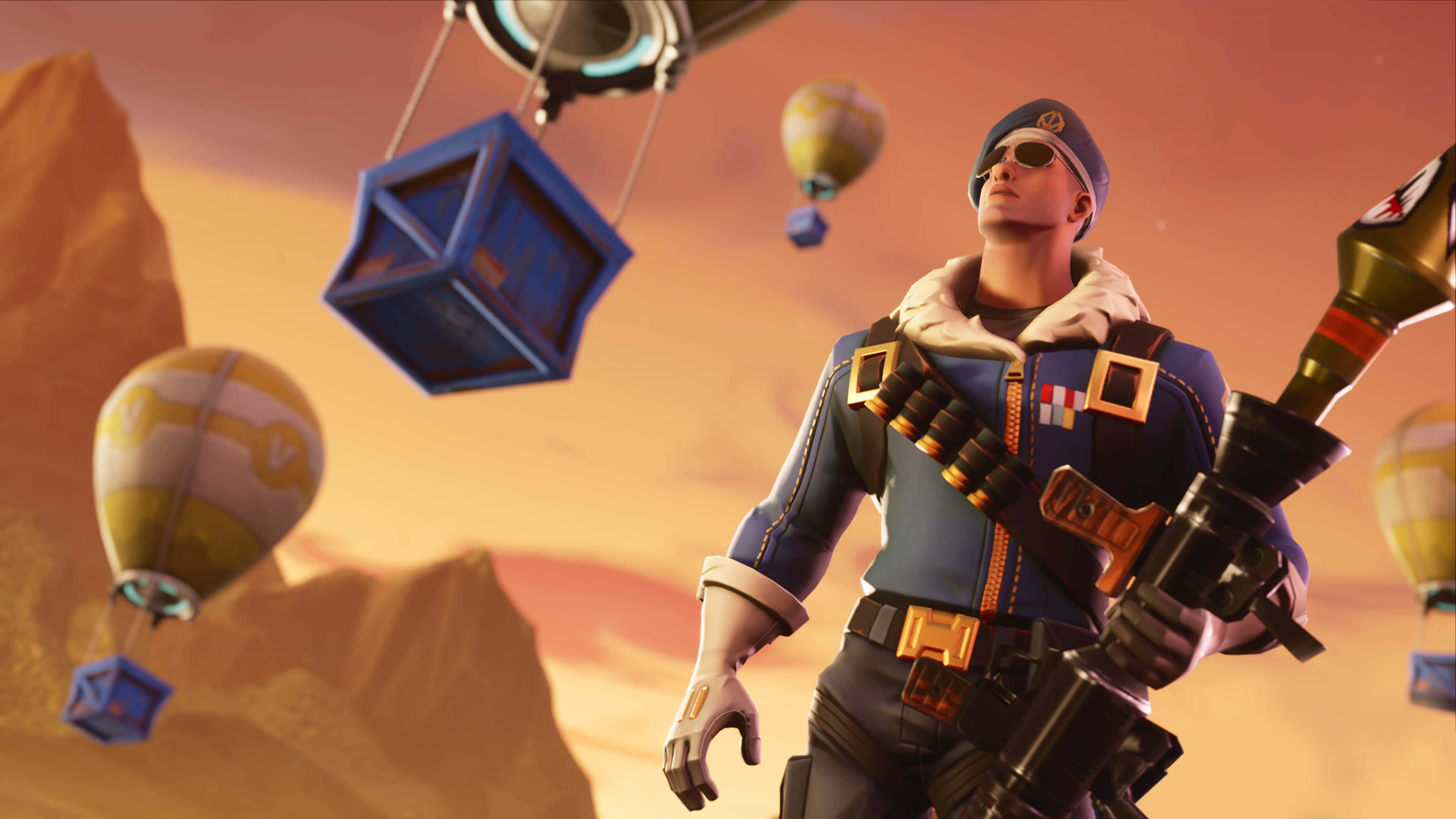 Fortnite 桌布 壁紙 — 一名身穿藍色制服和太陽眼鏡的士兵站在沙漠峽谷中，手持火箭發射器，色彩繽紛的熱氣球和漂浮的立方體飄過。