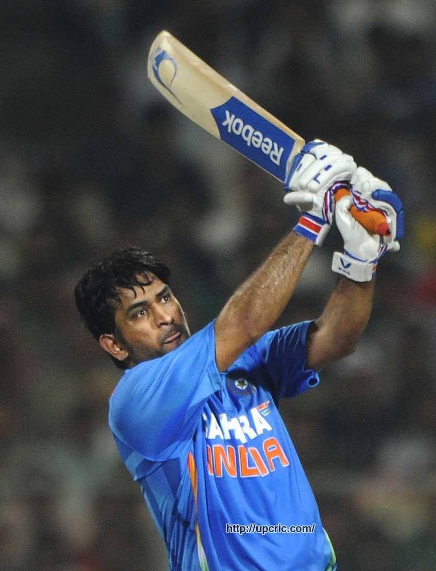 Ms Dhoni 桌布 壁紙 — 一名身穿藍色印度球衣的板球運動員在體育場燈光下的夜間比賽中，專注地揮動Reebok球棒。