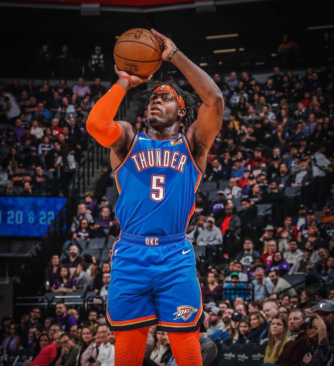 NBA 桌布 壁紙 — 一名身穿藍色和橙色雷霆球衣的籃球運動員在明亮的燈光下，在擠滿觀眾的體育館中投籃。
